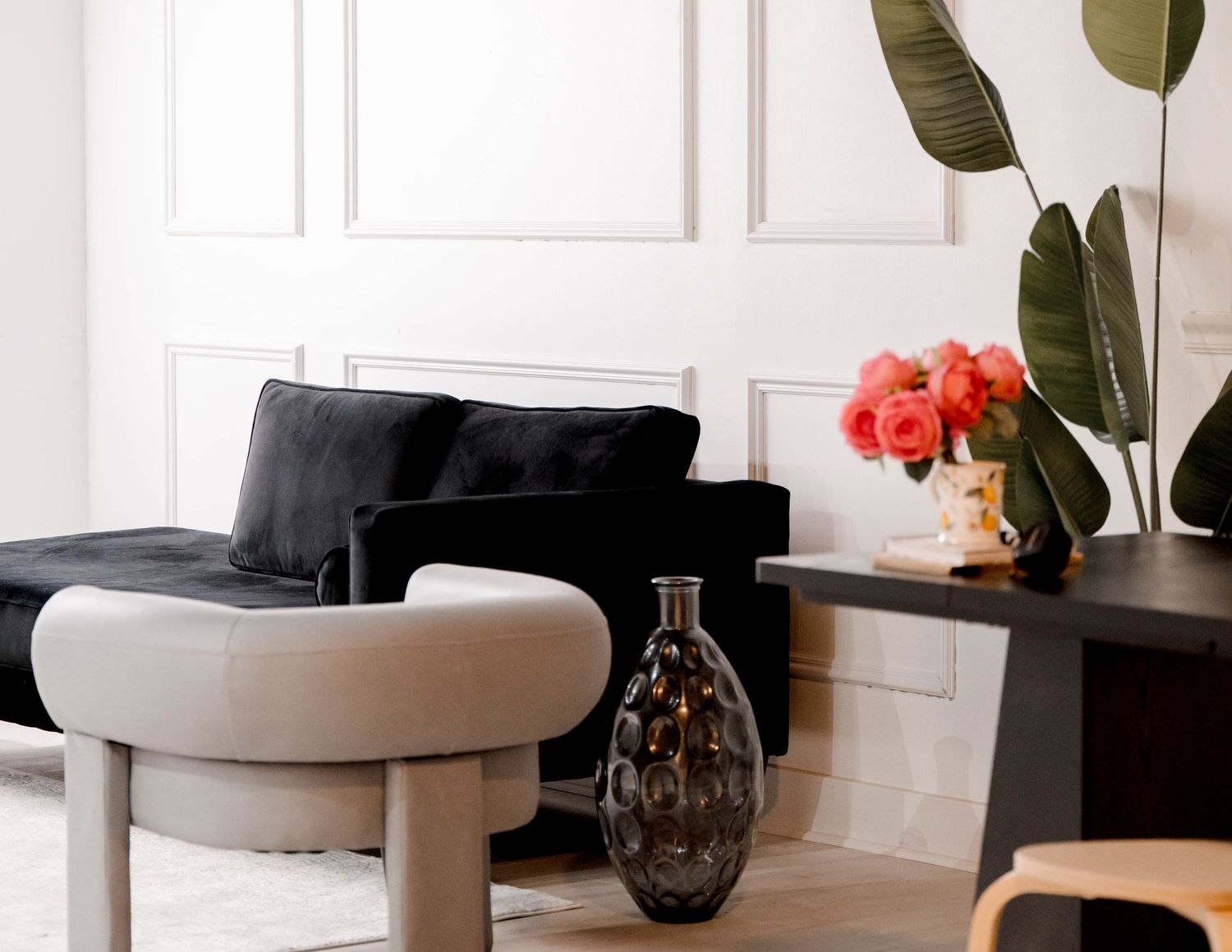Modern living room featuring curved furniture and large tropical plants in a bright, airy space.