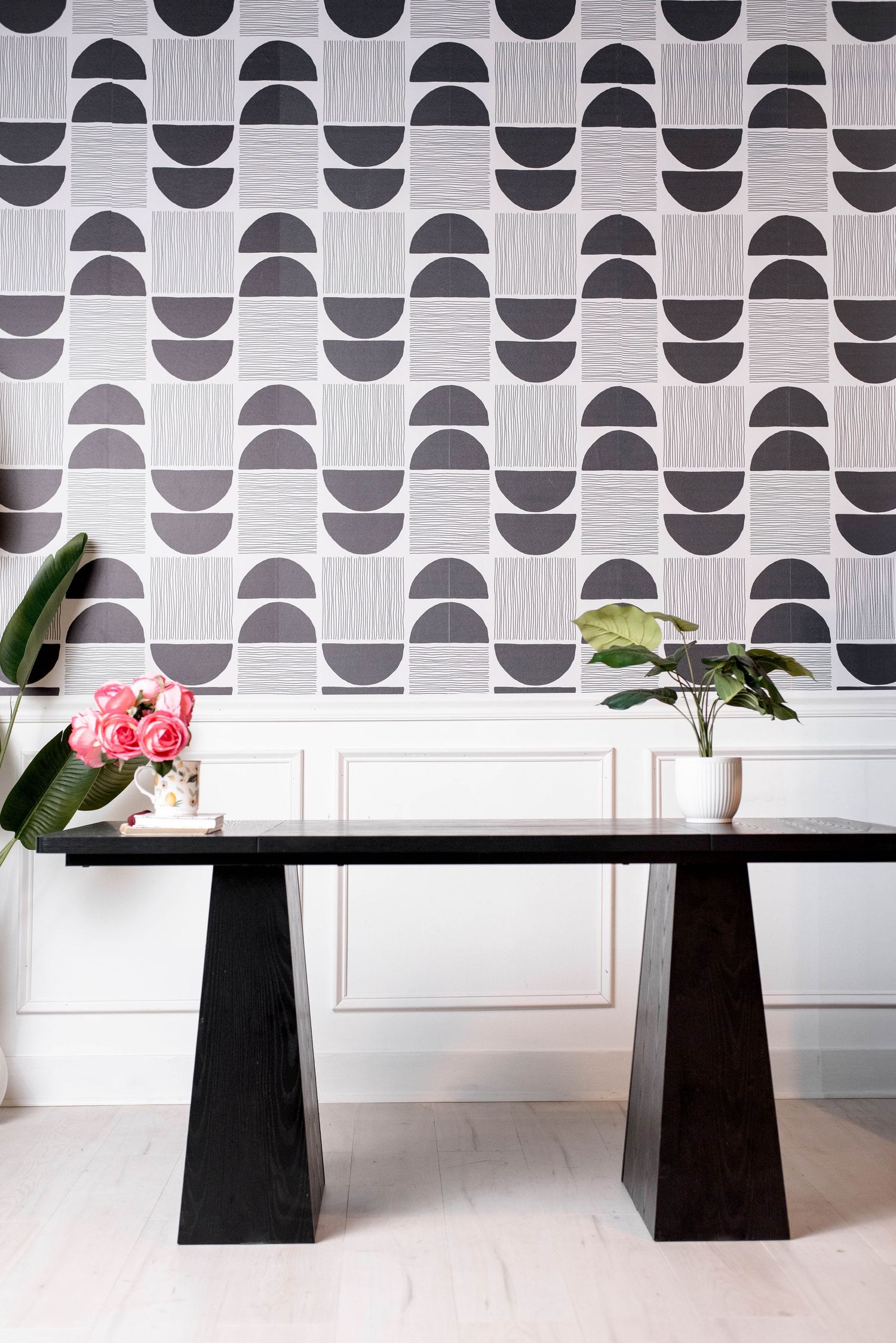 Modern geometric wallpaper with black and white circles above sleek black pedestal table.