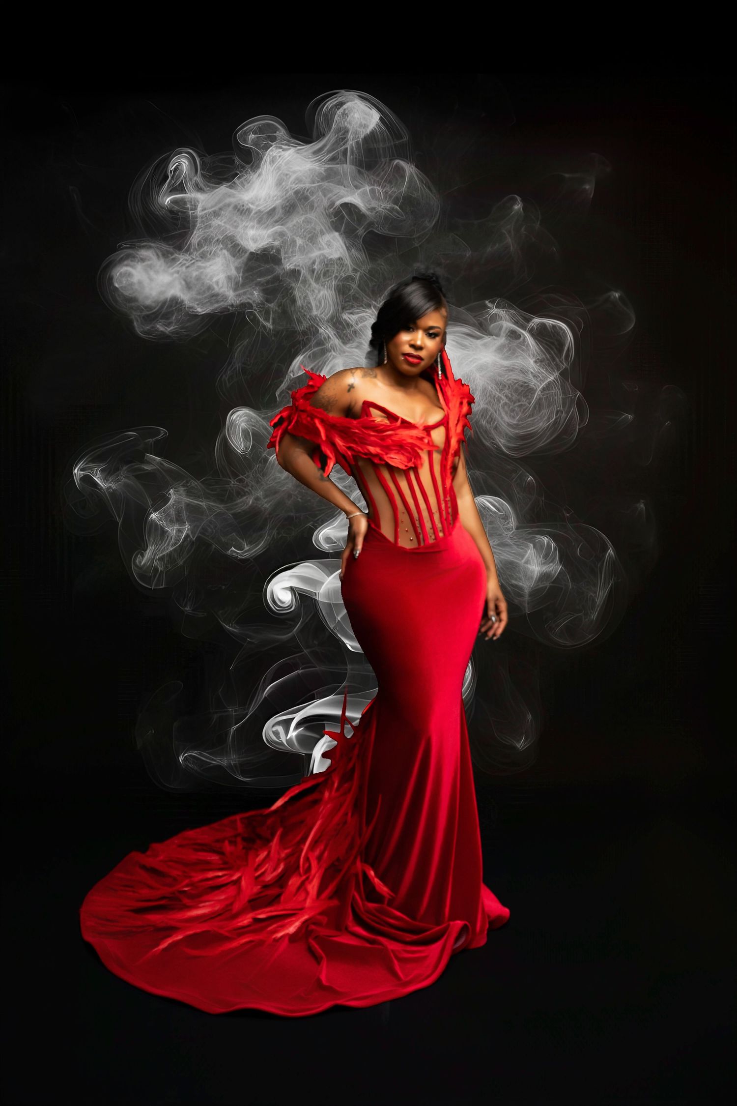 Woman in elegant red mermaid gown with feather details poses dramatically against black background with swirling white smoke.