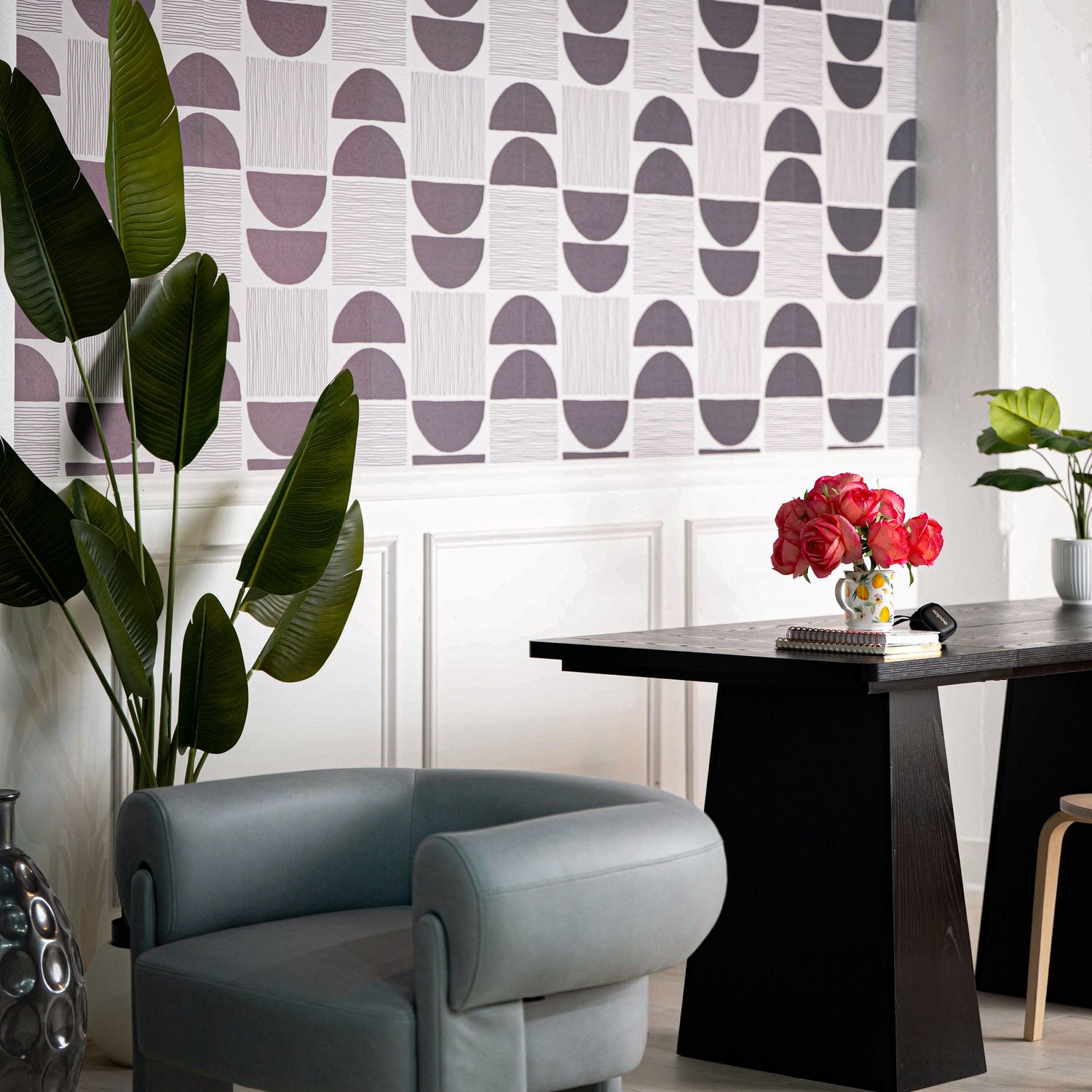 Modern seating area with geometric pattern wallpaper and sculptural furniture.
