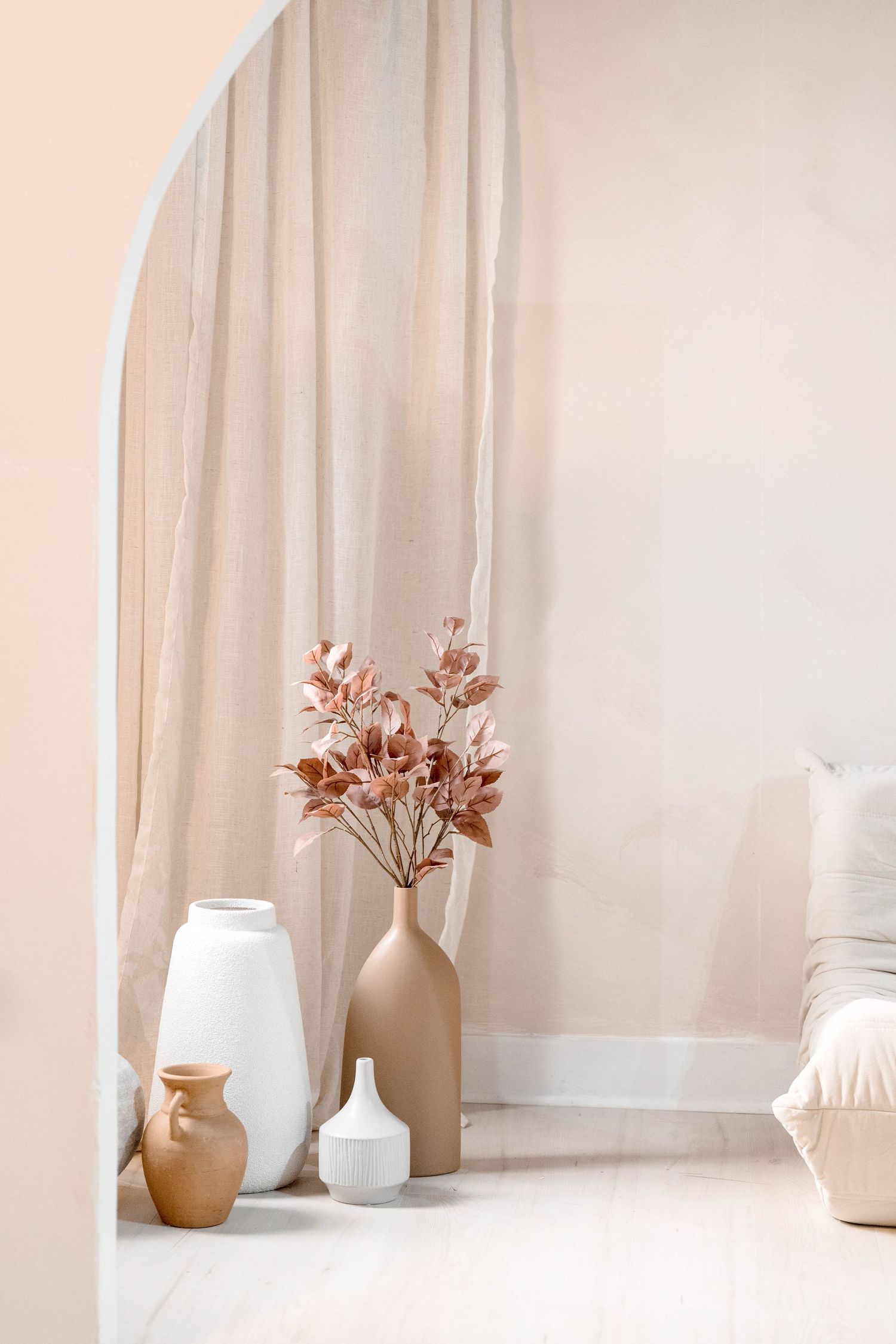 Collection of neutral ceramic vases and vessels styled on white surface with soft lighting.