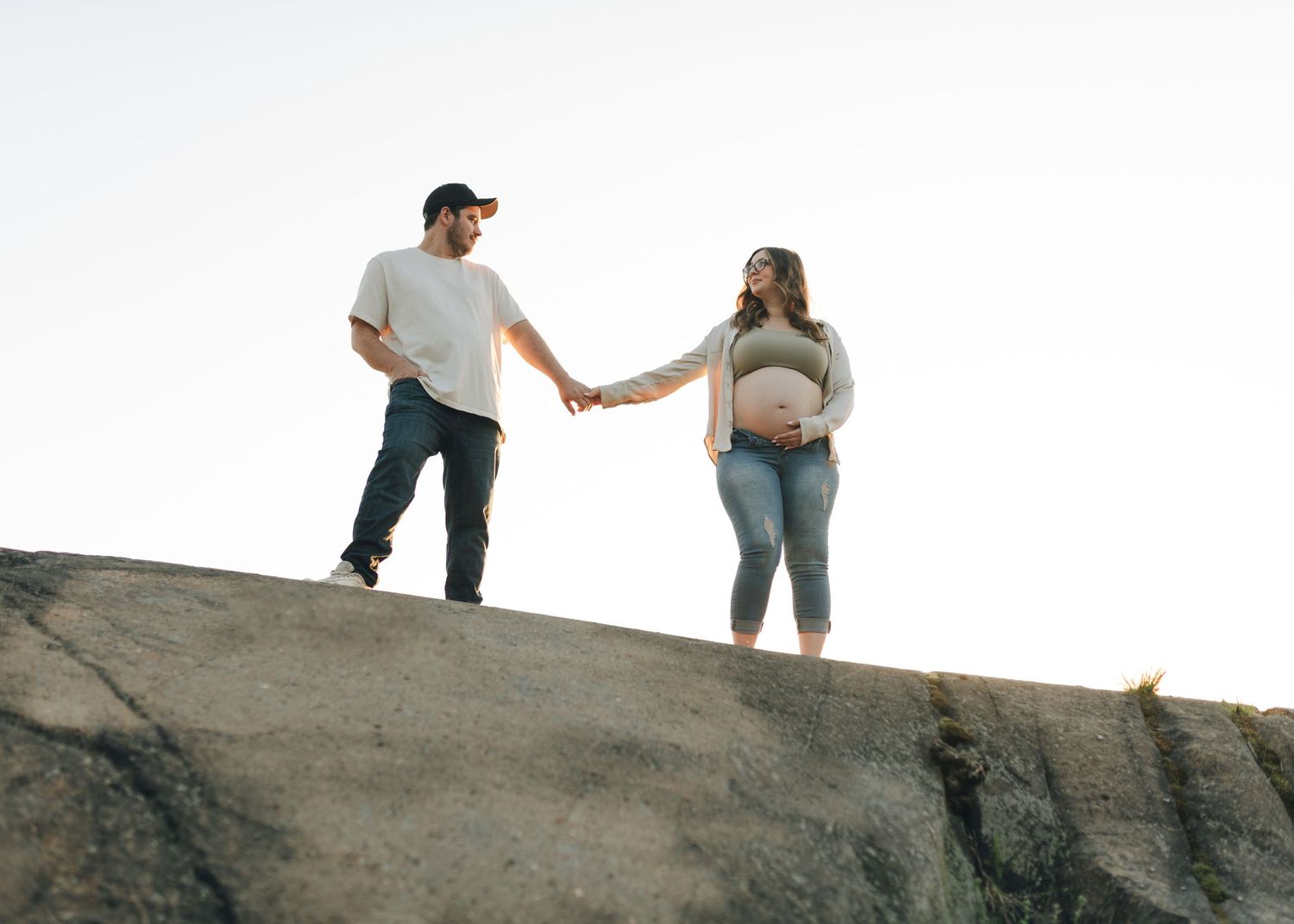 Couple holding hands while standing on rocky coastal terrain.