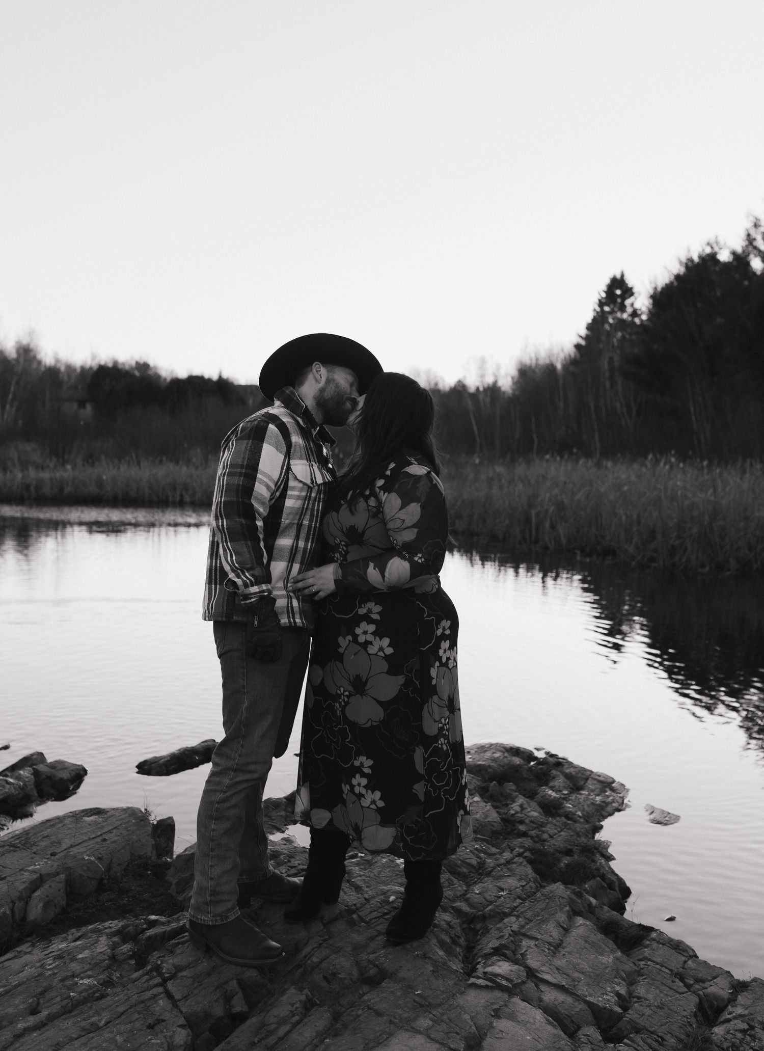A romantic black and white photo sequence shows a couple sharing tender moments by a serene lakeside at sunset.