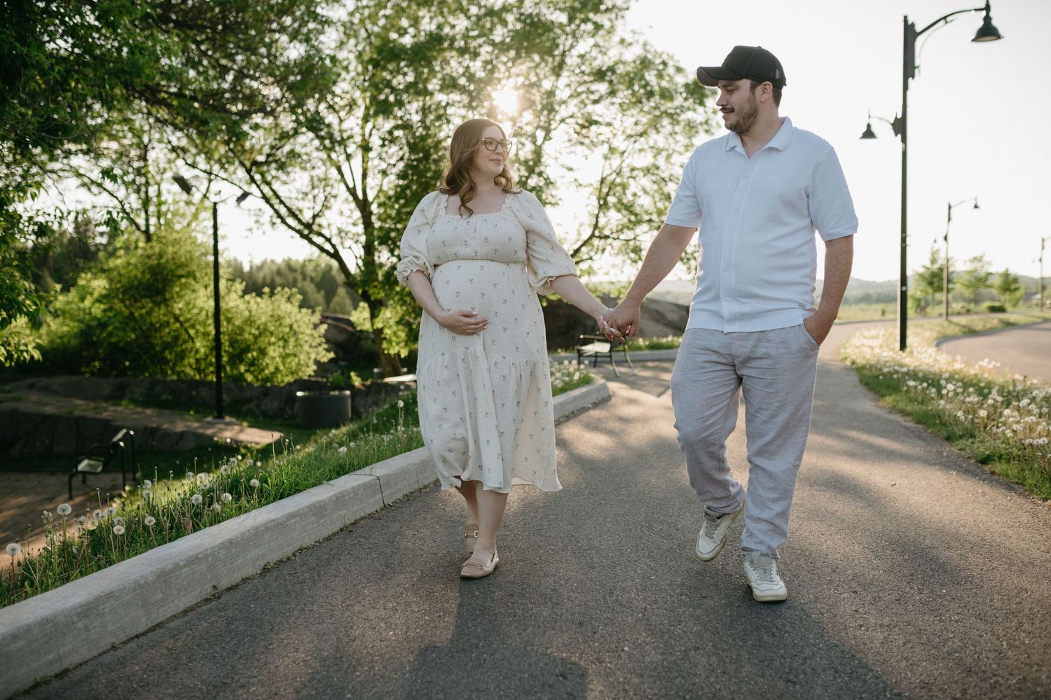 A couple walks together on a paved path surrounded by greenery.