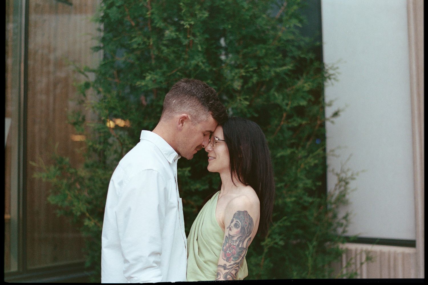 Couple shares intimate moments in a series of four romantic outdoor photos with greenery in the background.