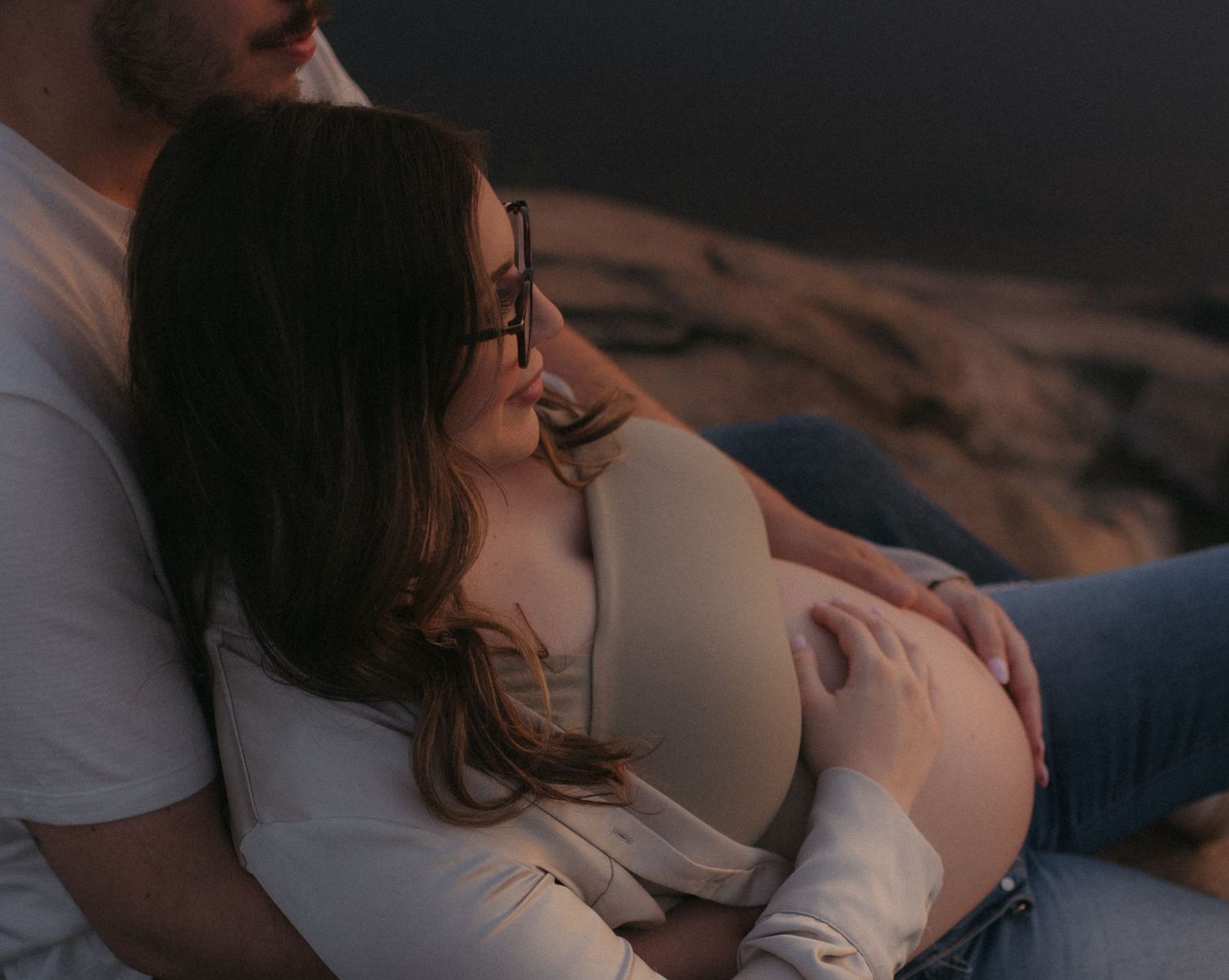 Moody indoor maternity photography session with soft natural lighting.