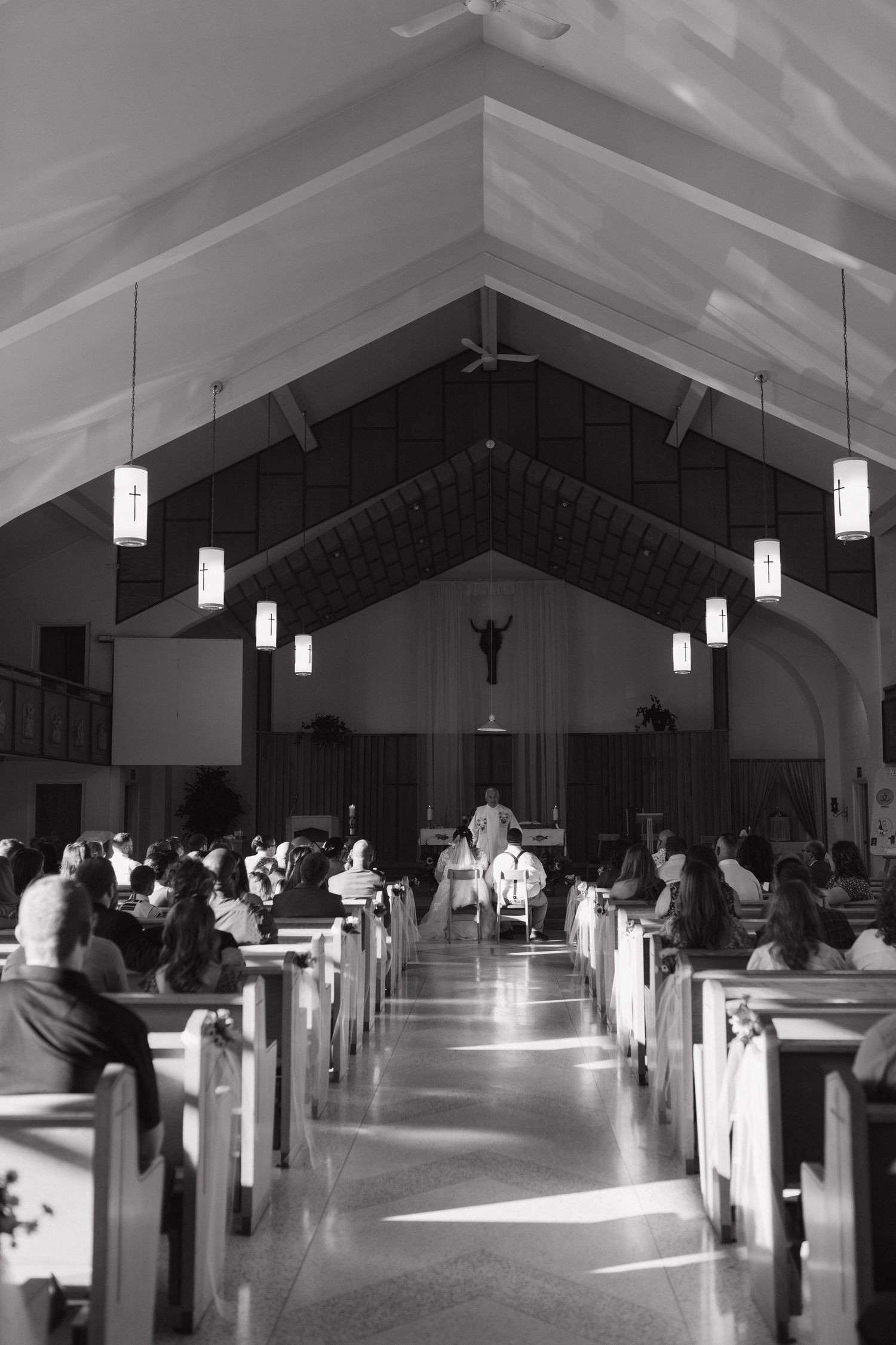 Black and white photo of church interior with dramatic lighting and pews.