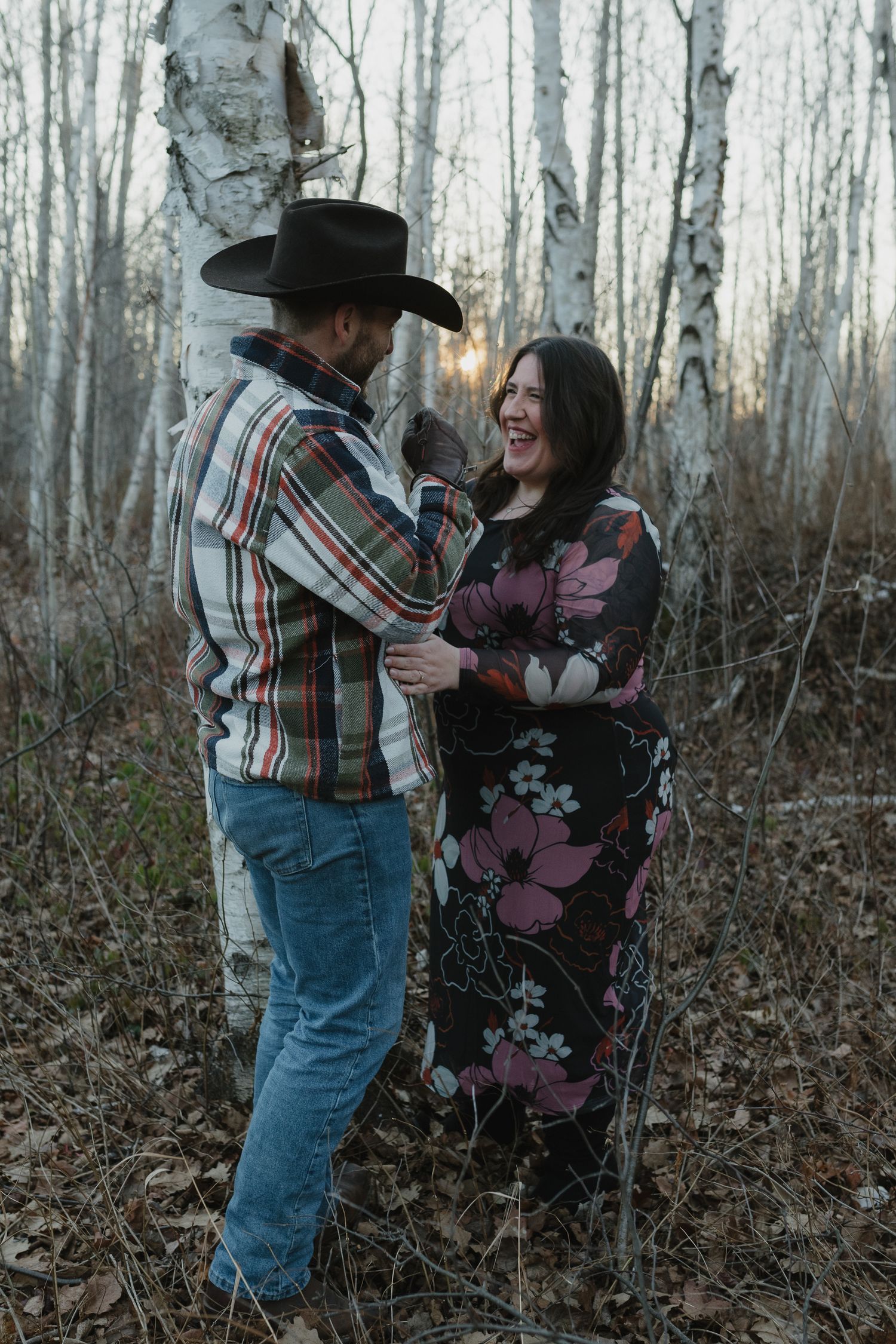 A couple dances together in a wooded area with birch trees during autumn.