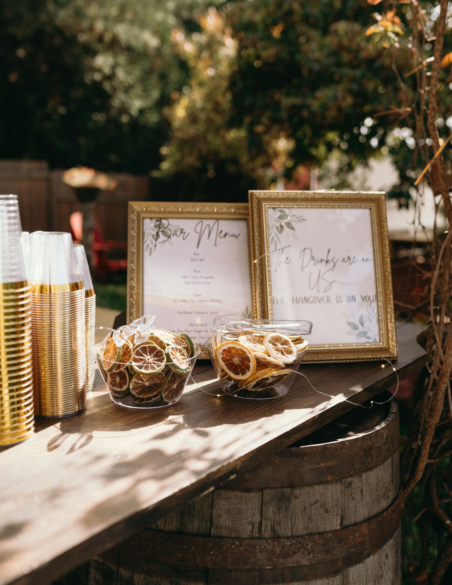 Elegant wedding reception table with framed signs, glassware and golden decor details in natural sunlight.