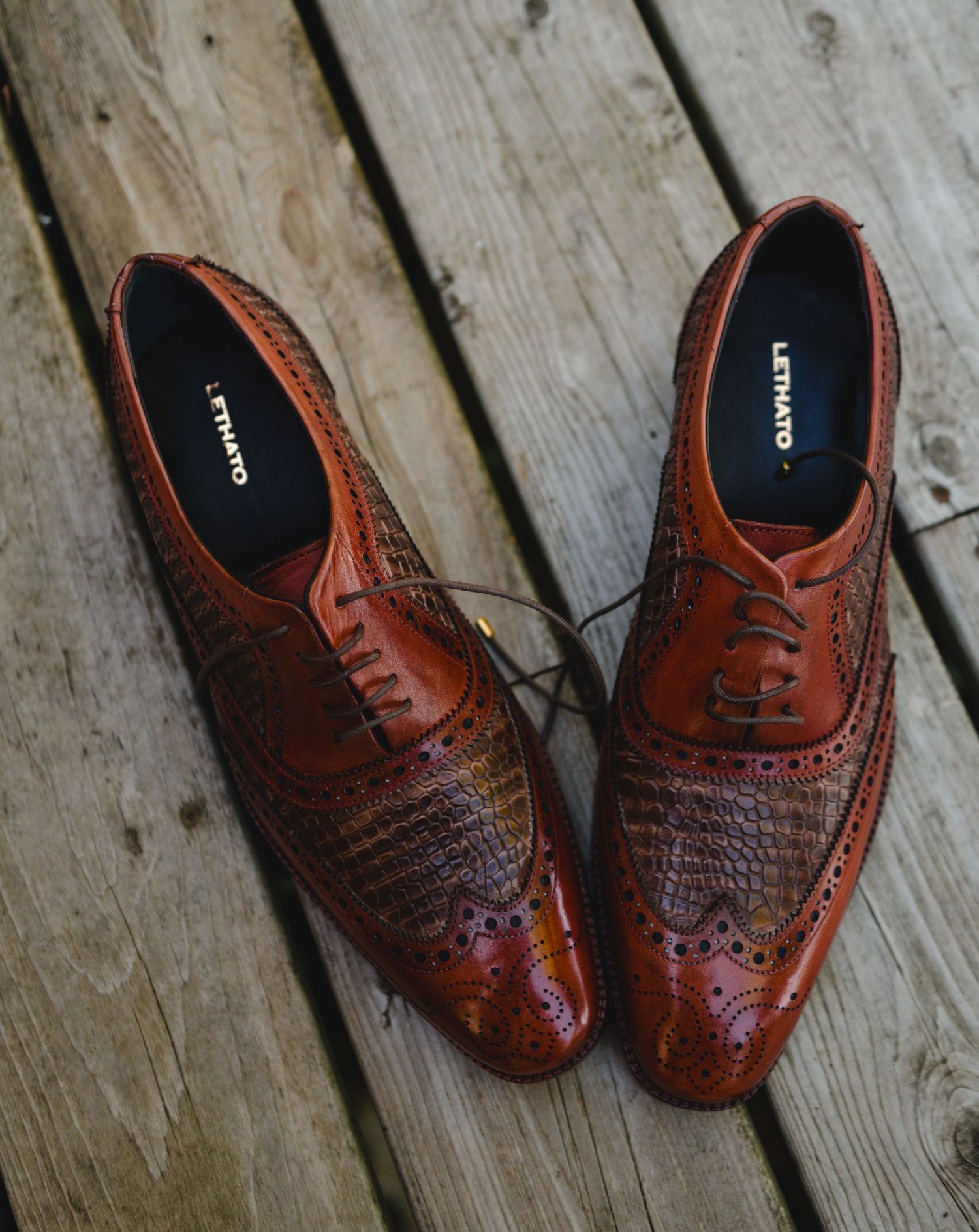 Brown leather brogue Oxford shoes by Lenato displayed on wooden deck surface.