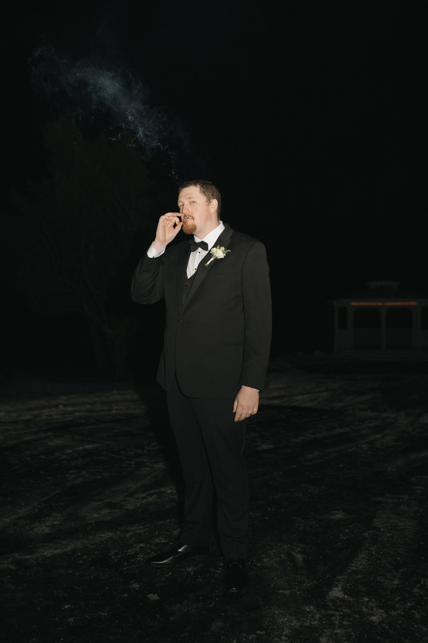 Four dark nighttime photos show someone in formal black attire posing against a shadowy outdoor background.