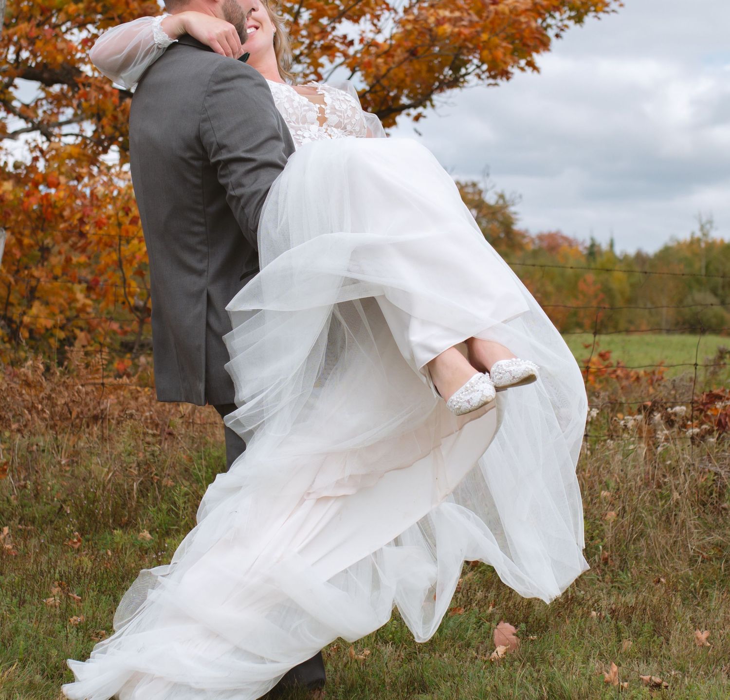 Wedding couple in playful dip pose amid autumn foliage.