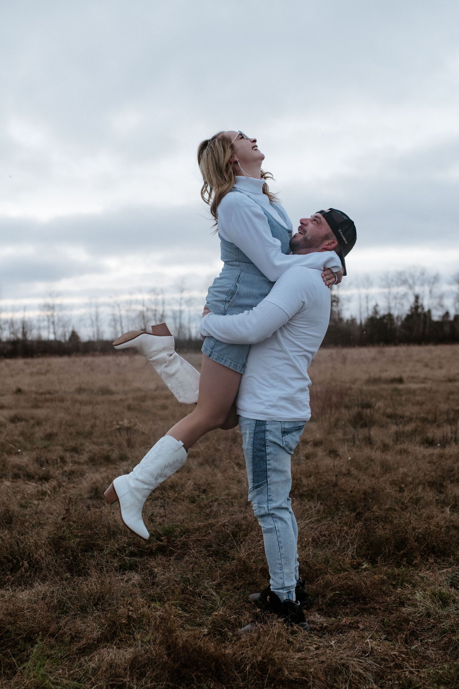Romantic couple embracing in an open field during golden hour.