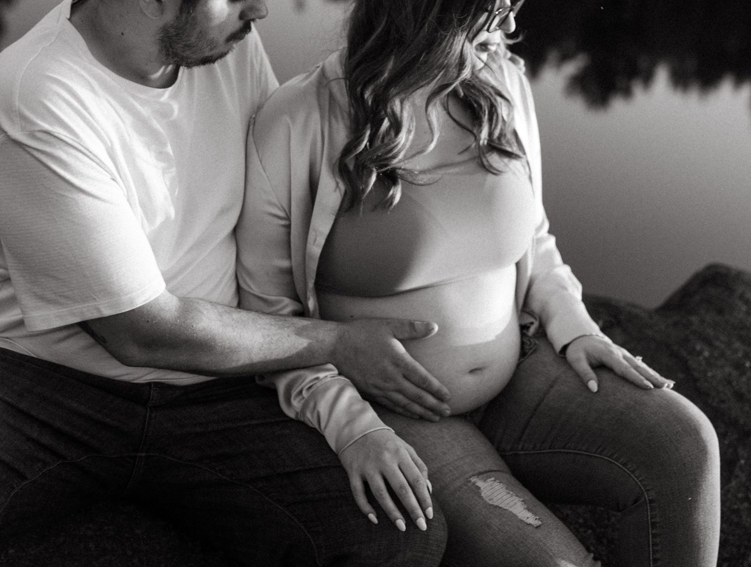 Black and white maternity photo showing a tender moment between expectant parents.