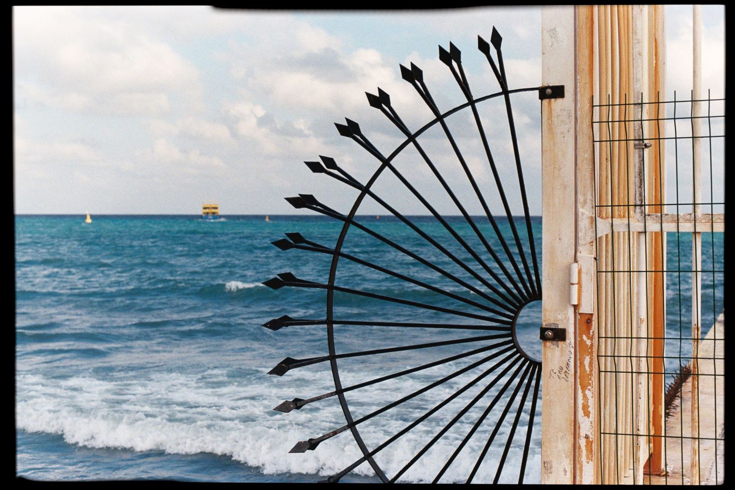 Decorative metal fan and bamboo elements create architectural detail against ocean backdrop.