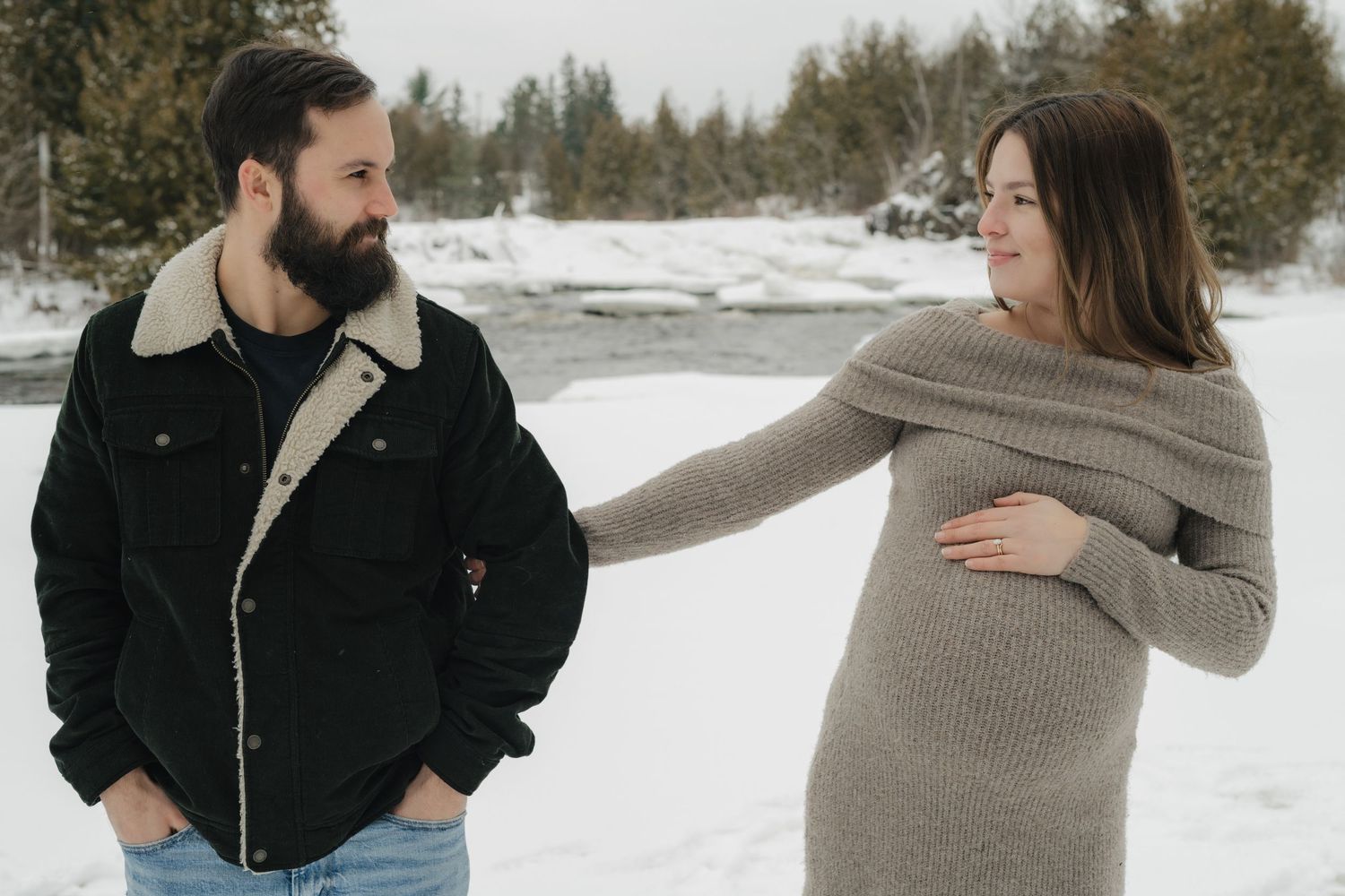 A couple in winter clothing poses together in a snow-covered setting.