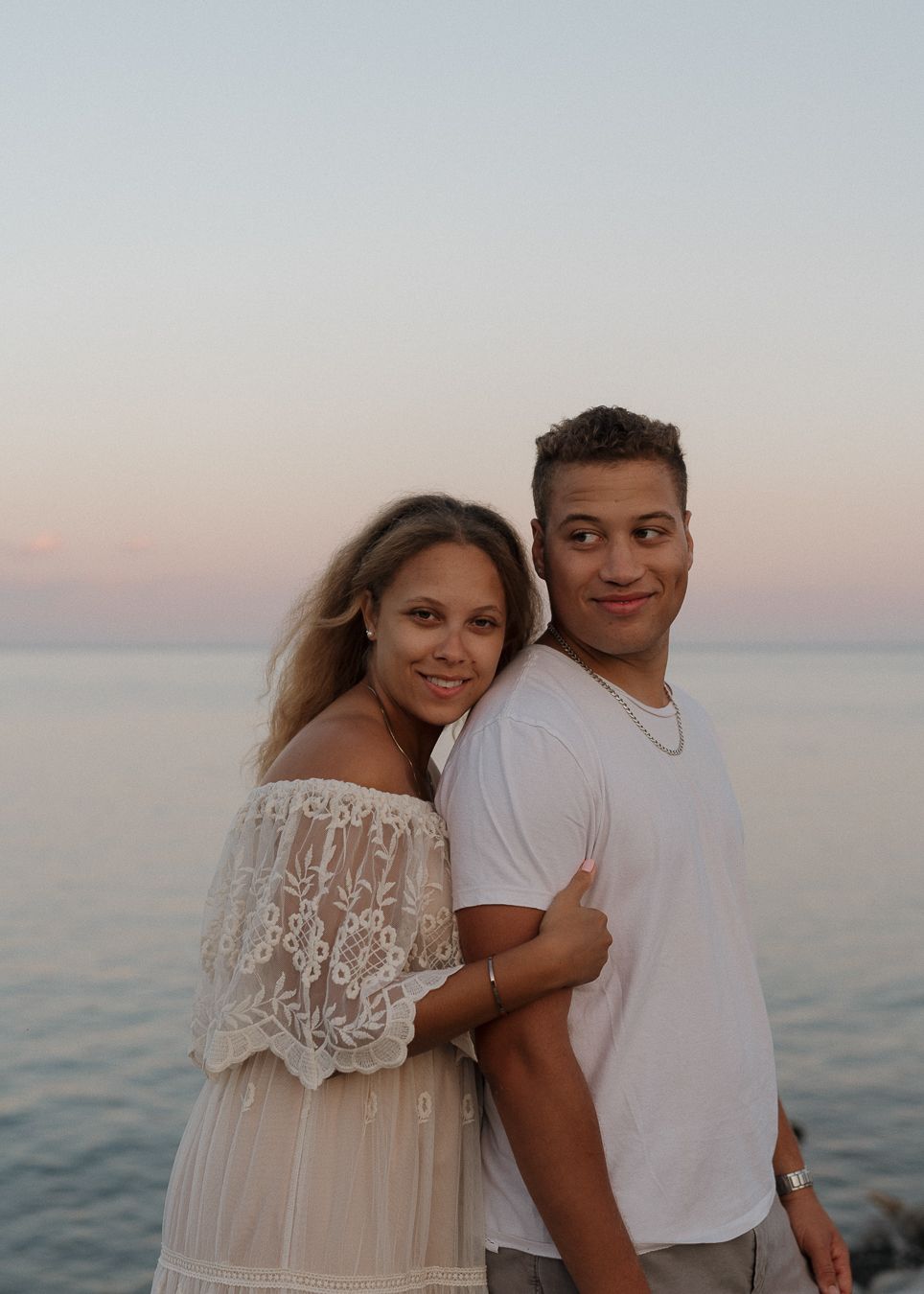 Romantic couple embraces at sunset by the ocean in a series of candid moments.