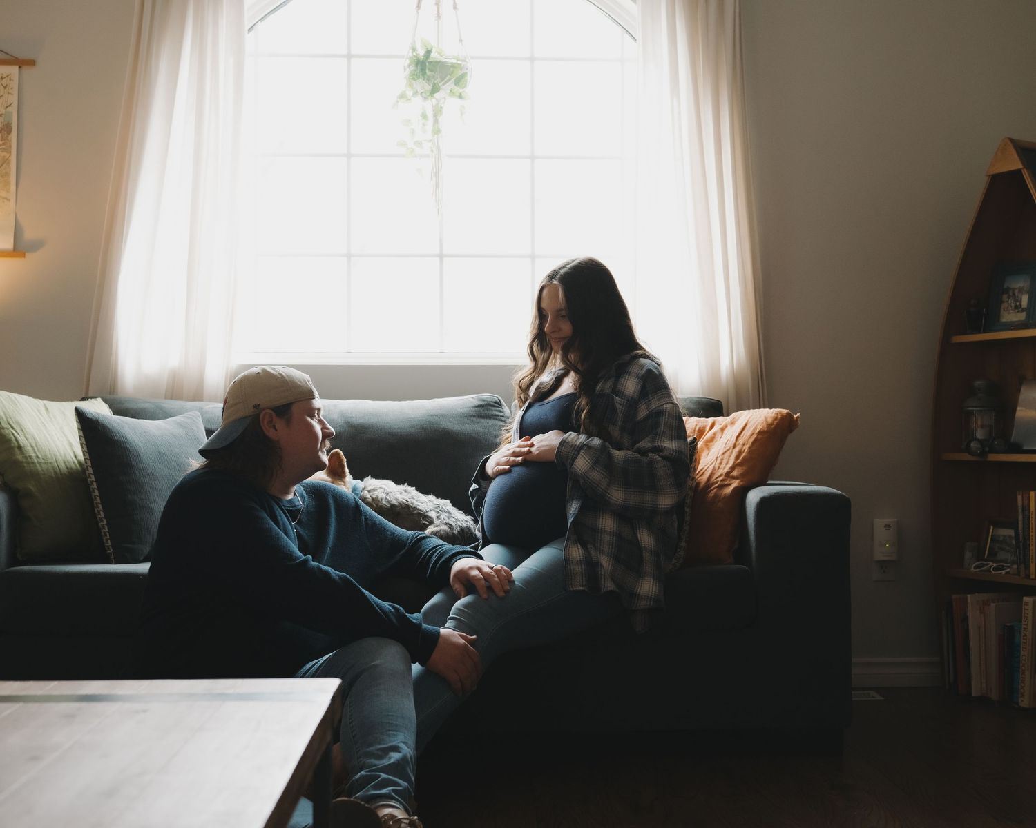 An intimate moment shared on a cozy couch by a bright window with flowing curtains.