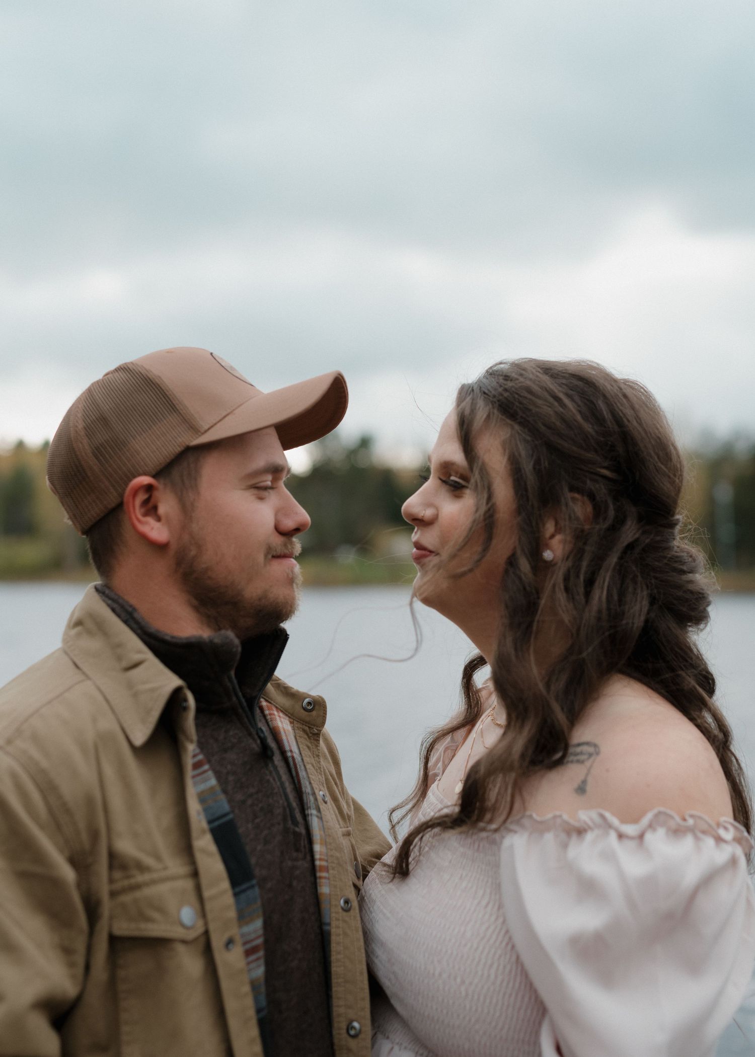 A couple in casual attire share an intimate moment outdoors with a scenic natural background.