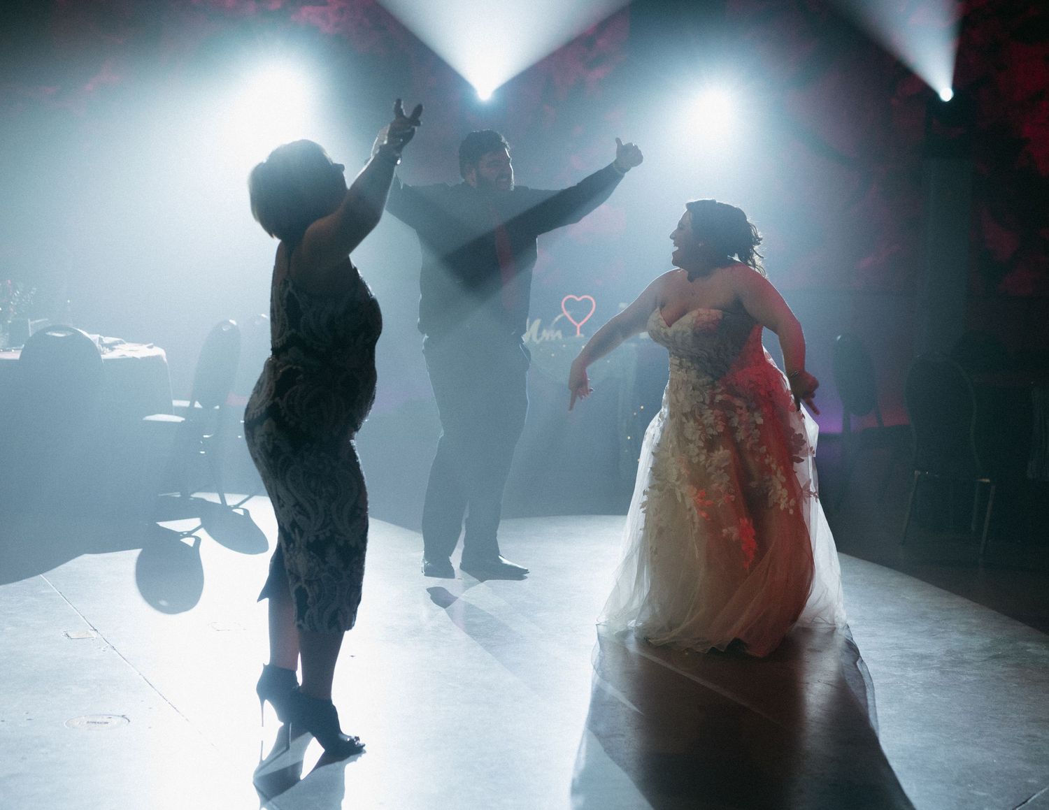 Silhouettes of people dancing in atmospheric fog with dramatic lighting effects.