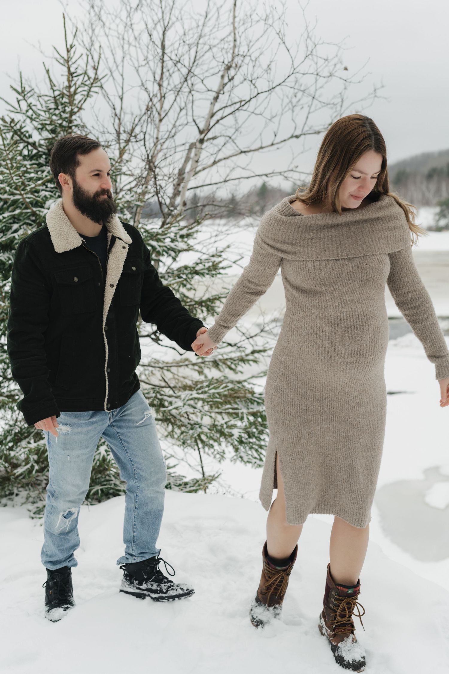 Candid winter photoshoot showing playful interaction between two people in the snow.