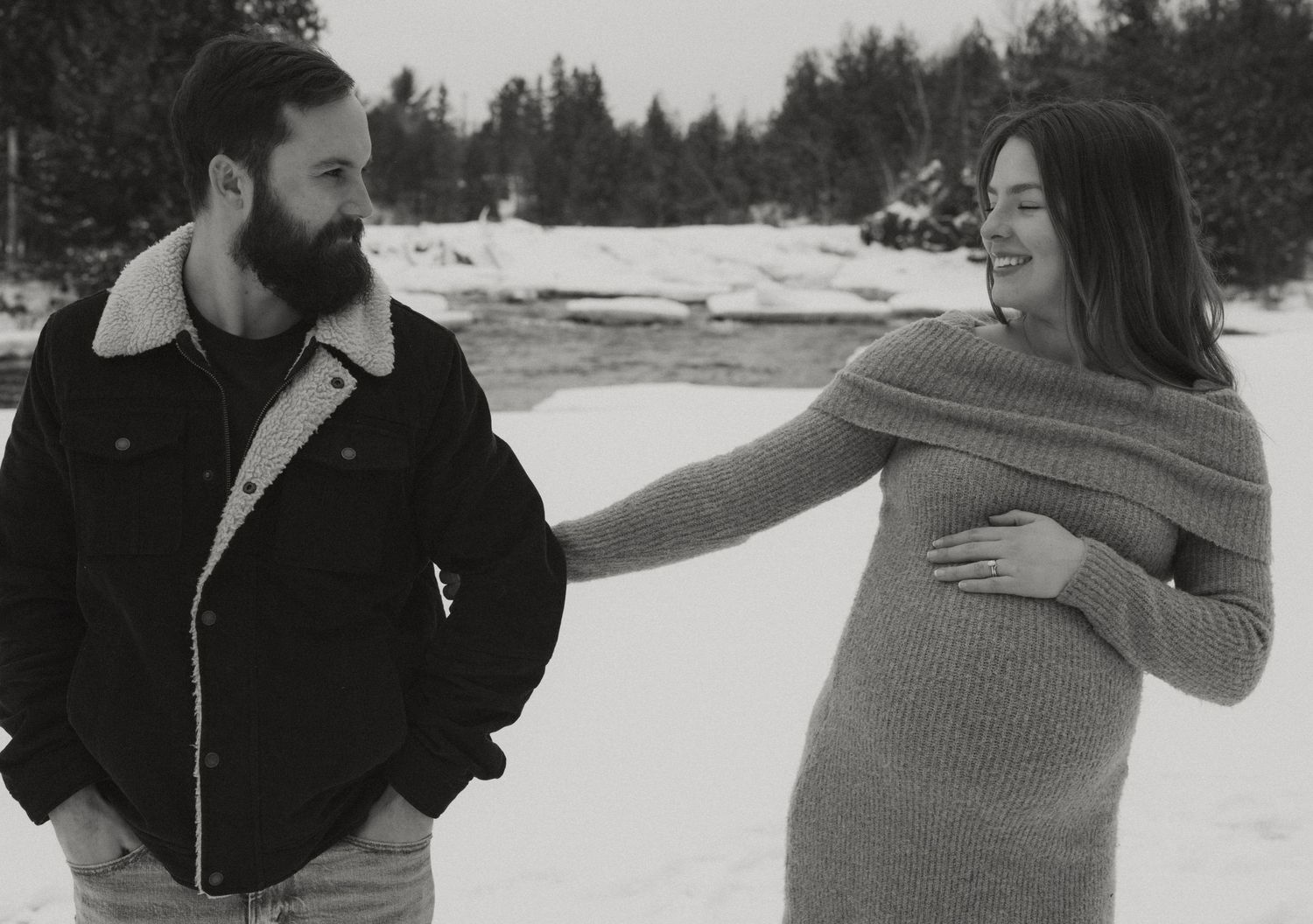 Two people share an intimate moment against a snowy forest backdrop.