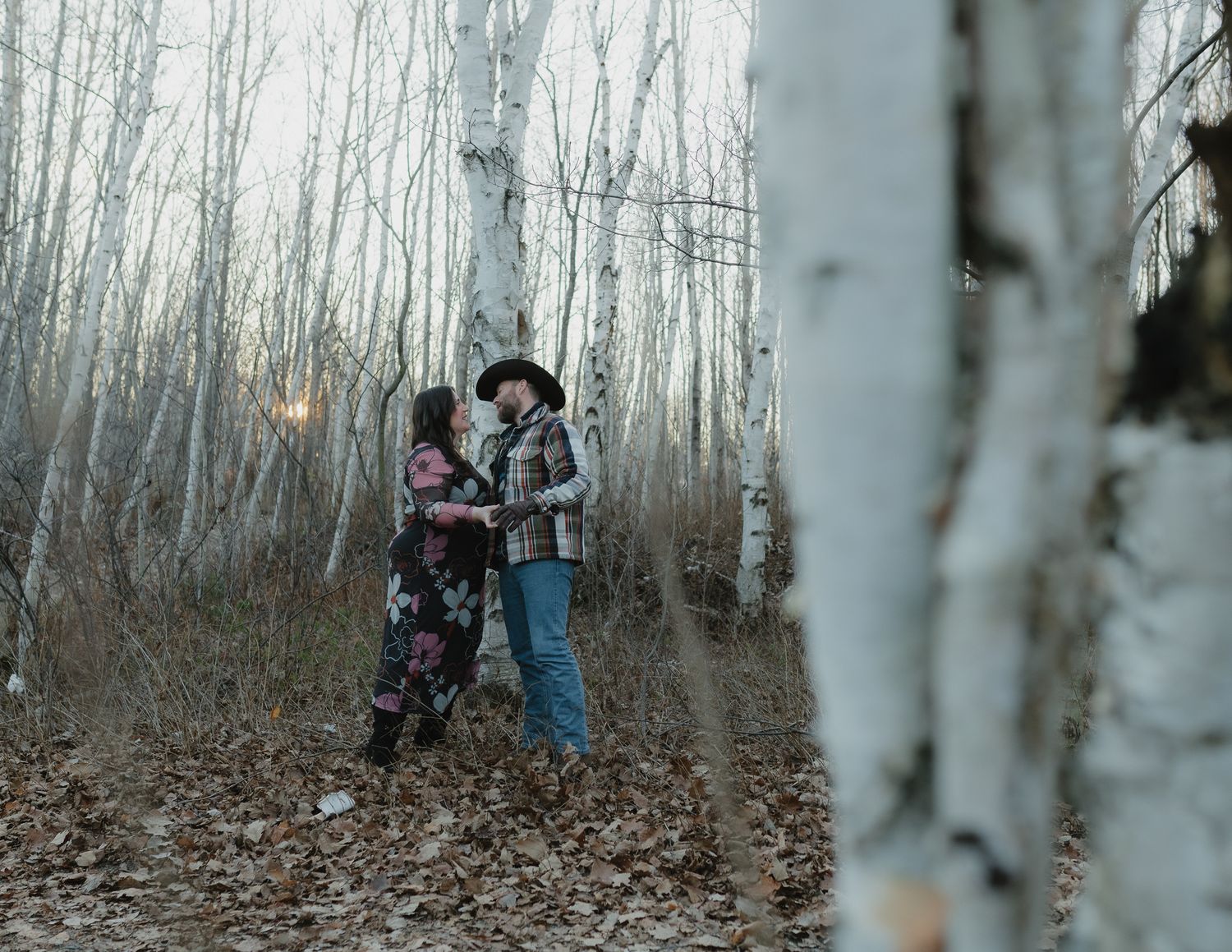 A couple embraces in a serene birch forest during an engagement photo session.