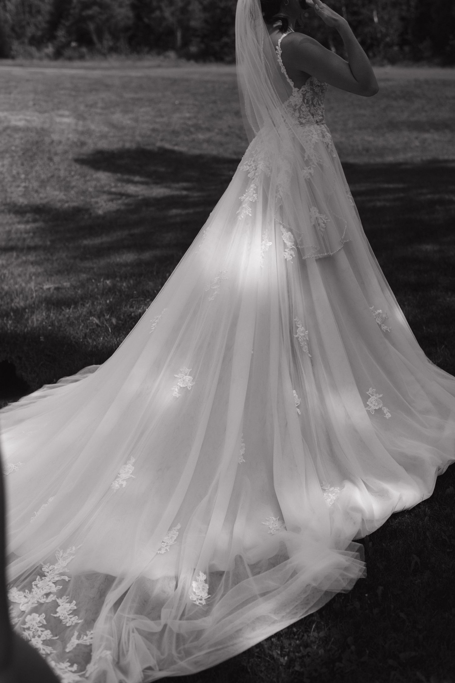 Dramatic black and white photo of a wedding gown's sweeping train and delicate lace details.