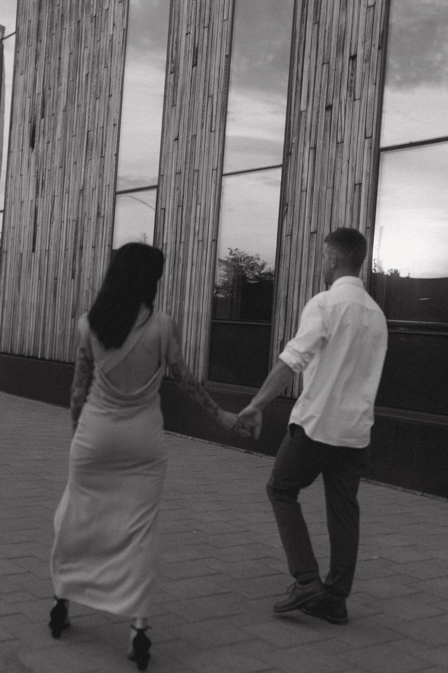 Couple holding hands while walking through downtown Sudbury by Place Des Arts during their engagement session
