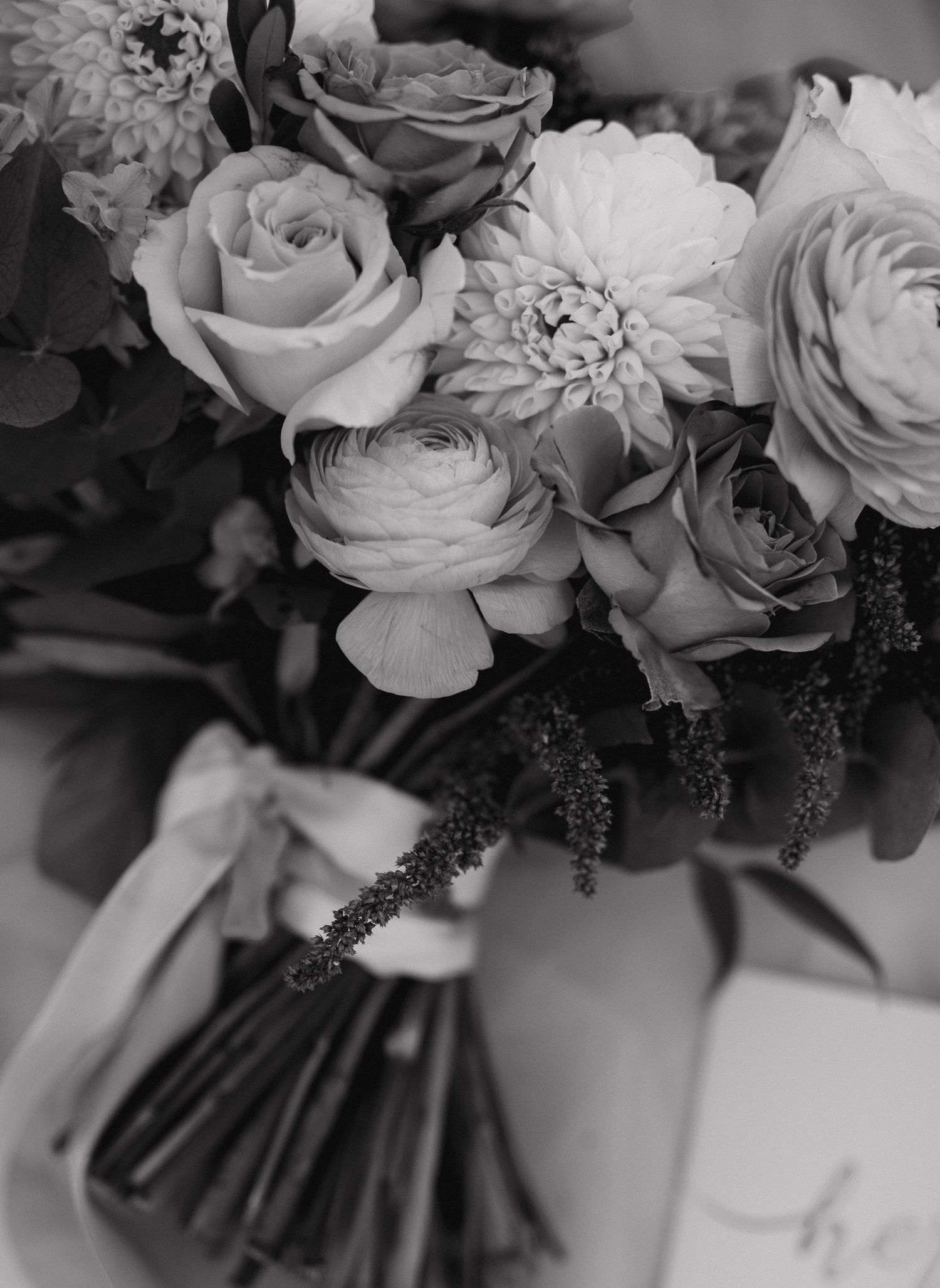Close-up black and white photo of a luxurious bouquet with roses and mixed flowers.