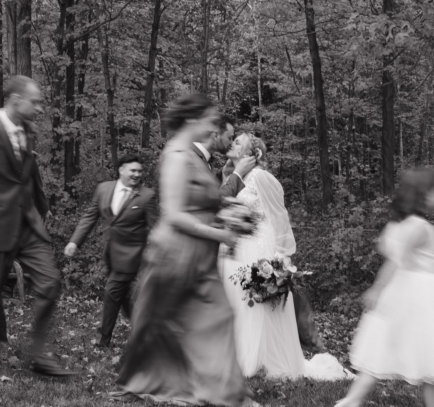 Motion blur captures wedding party walking through autumn forest.
