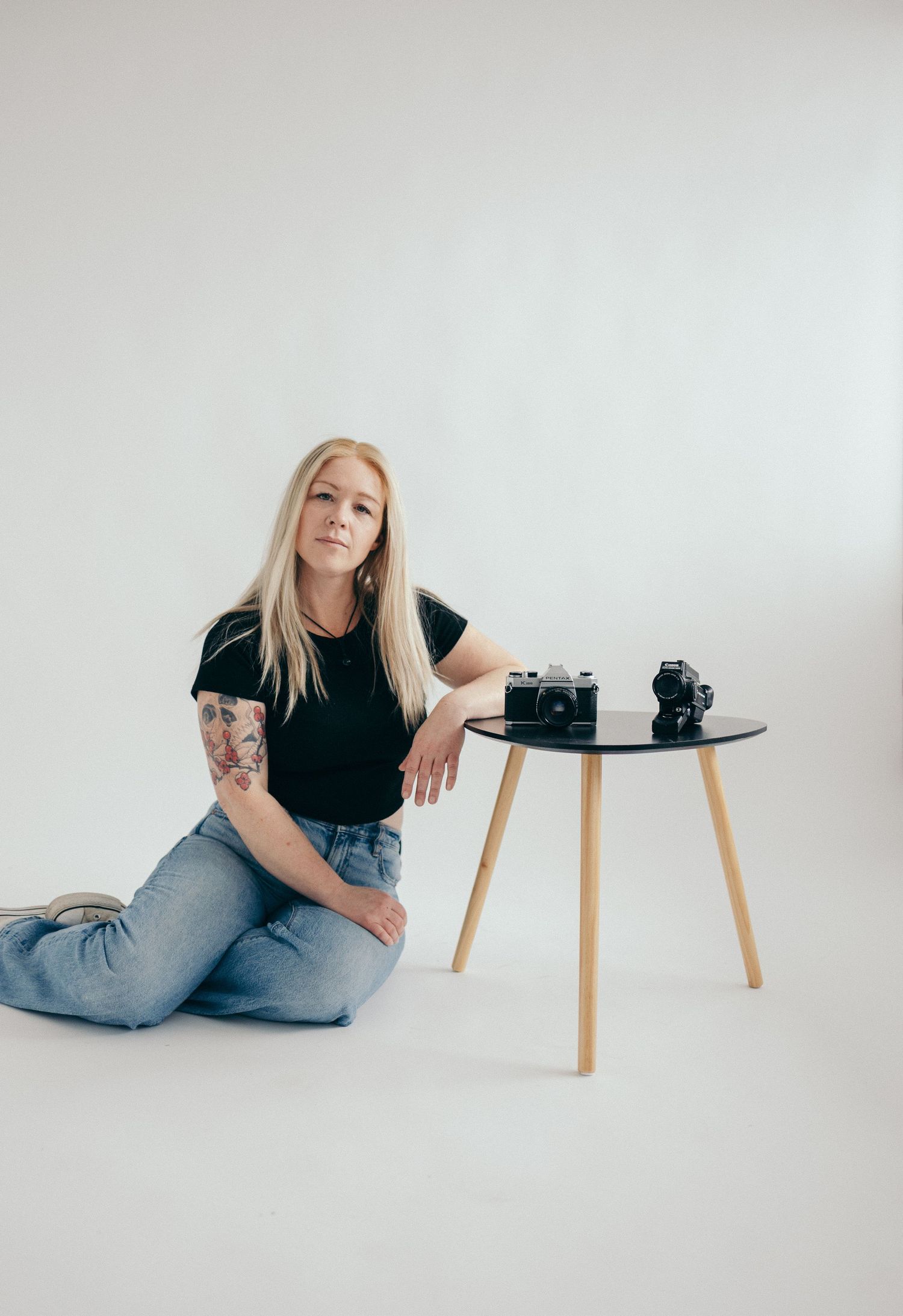 Minimalist studio setup with small table and camera equipment against white background.
