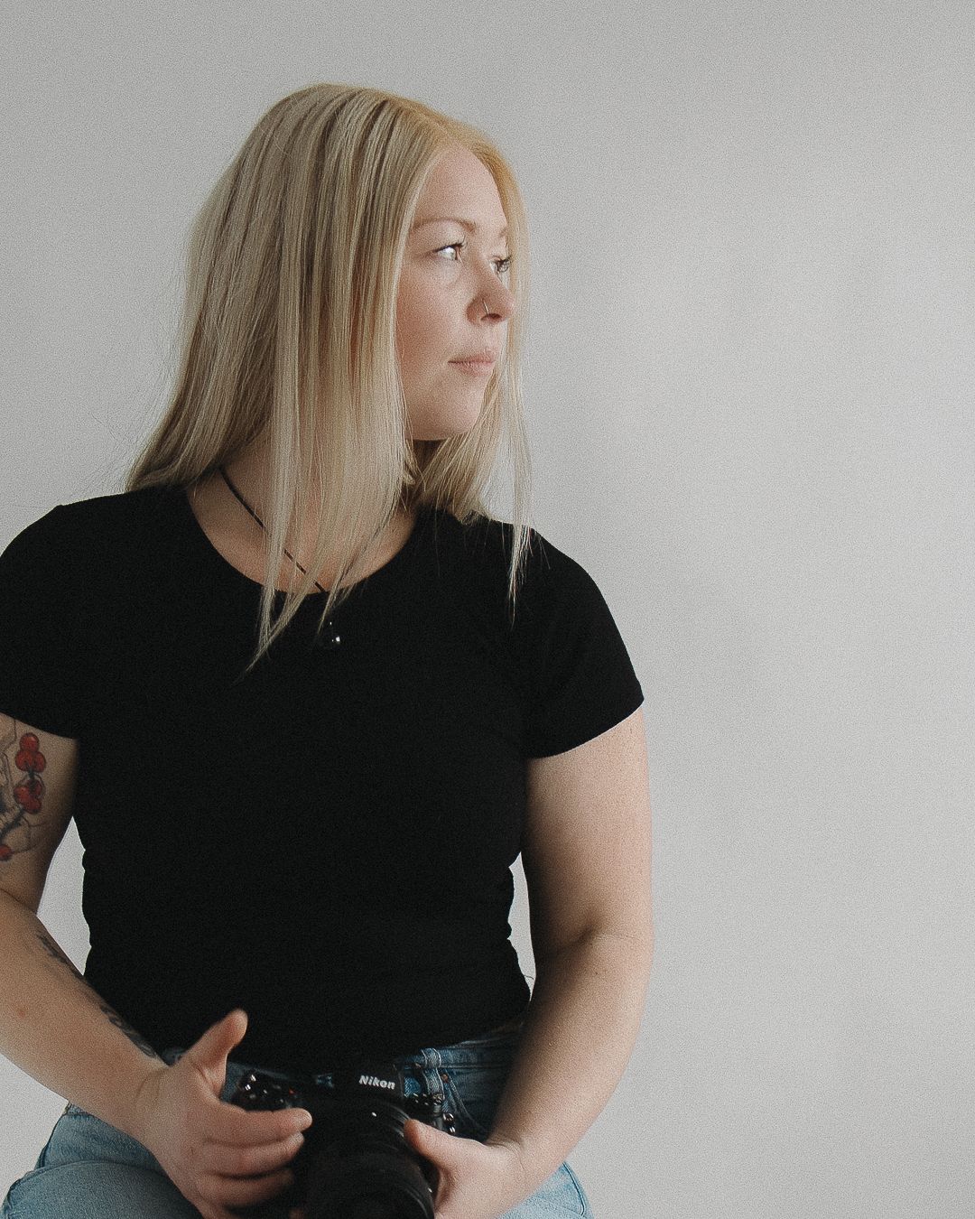 Studio portrait featuring casual black t-shirt and denim style against minimalist background.