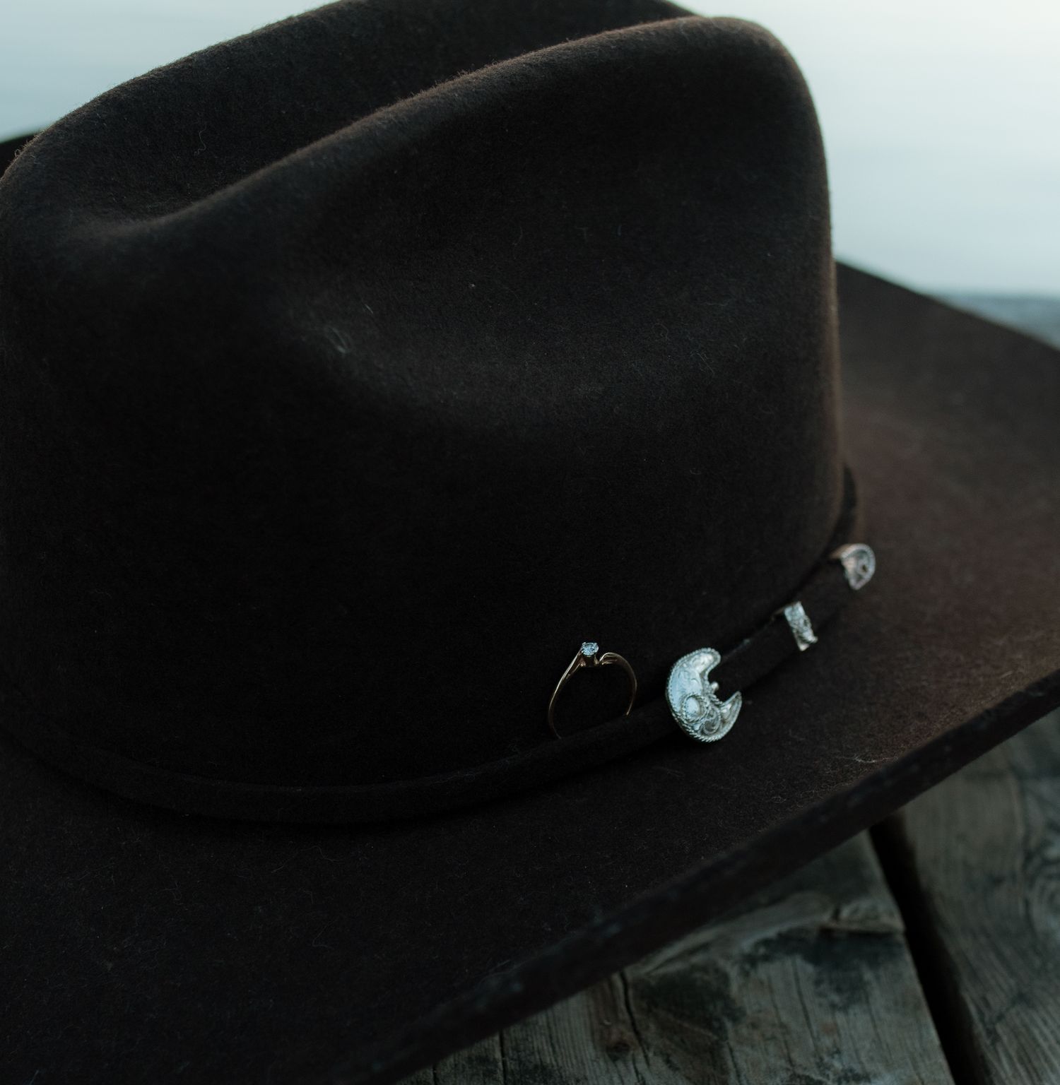 A black cowboy hat being rotated and shown from multiple angles on a dark wooden surface.