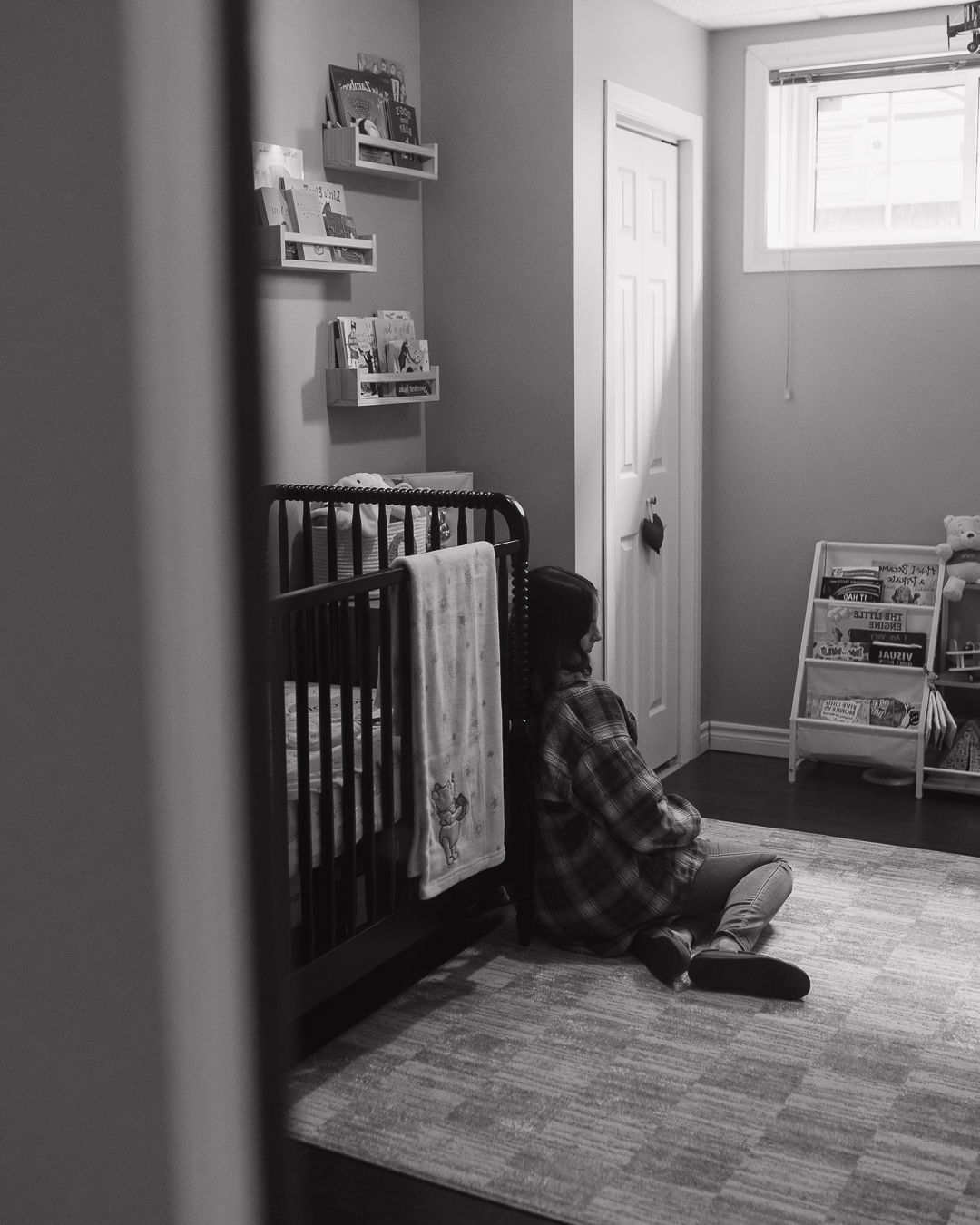 Black and white nursery room interior with a crib and minimal decor.
