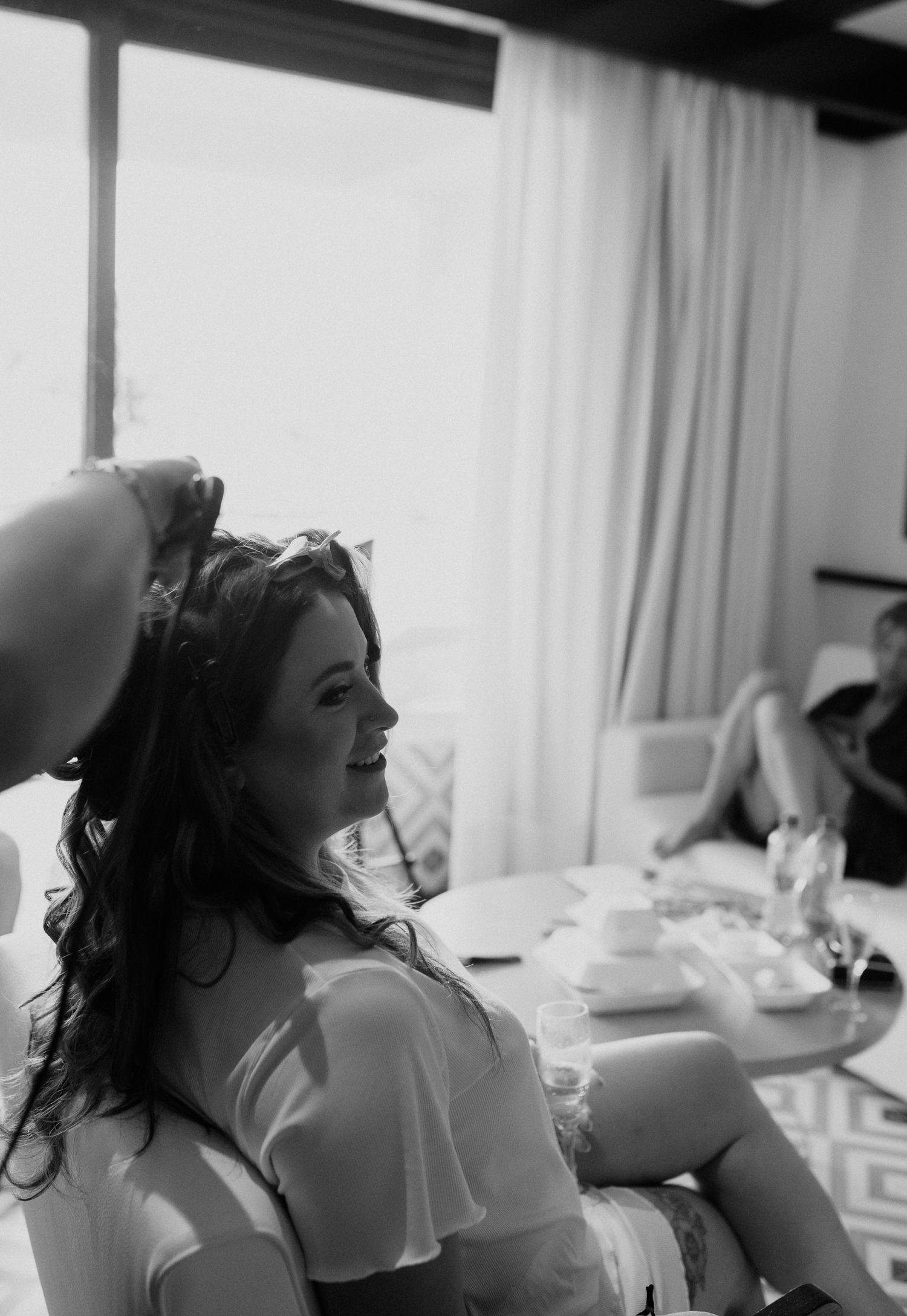 A black and white photo shows someone getting their hair styled while seated in a salon chair.