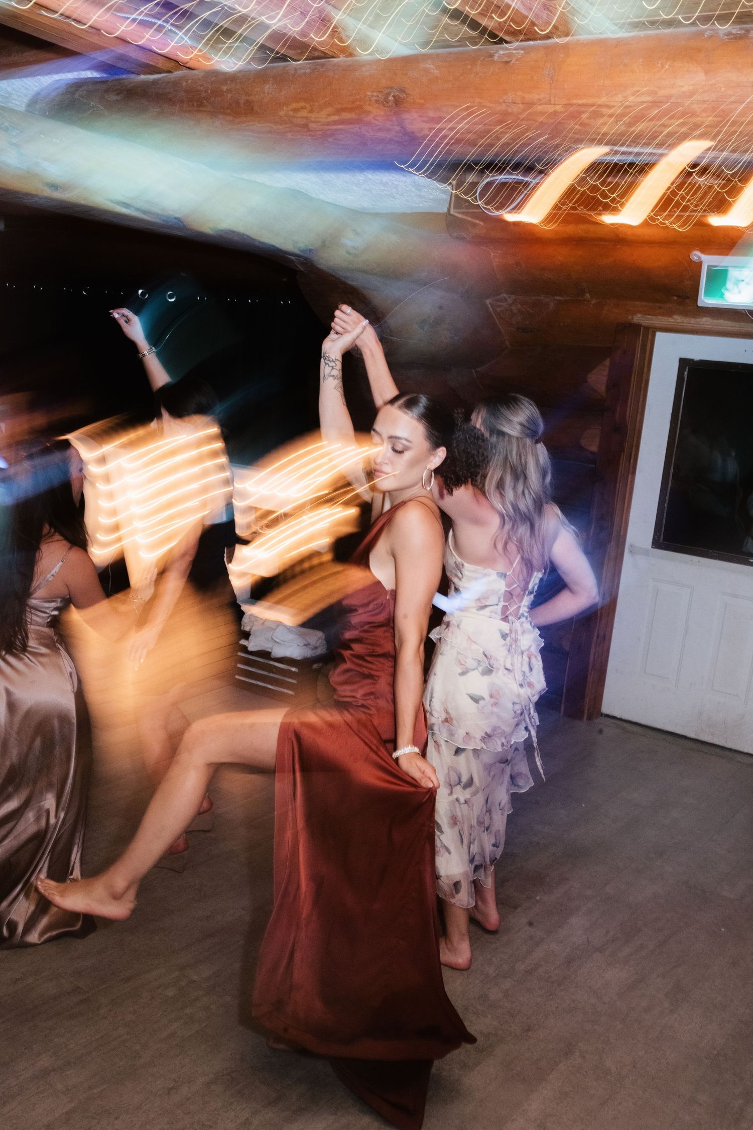 Women dancing at a wedding reception with motion blur and dramatic lighting effects.