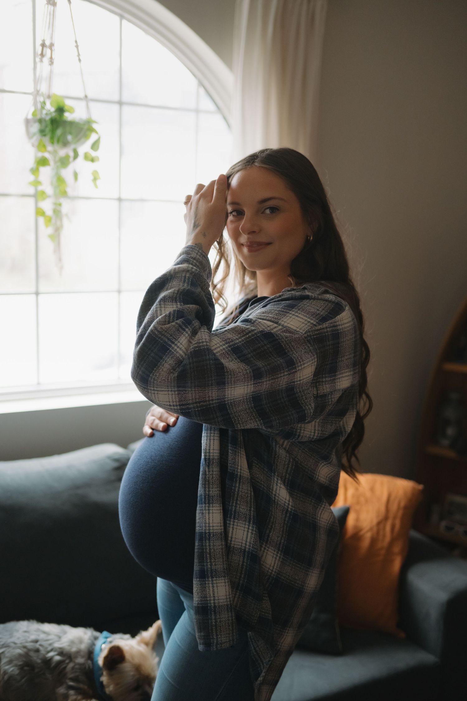 Person in plaid shirt sitting by window with natural light streaming in.
