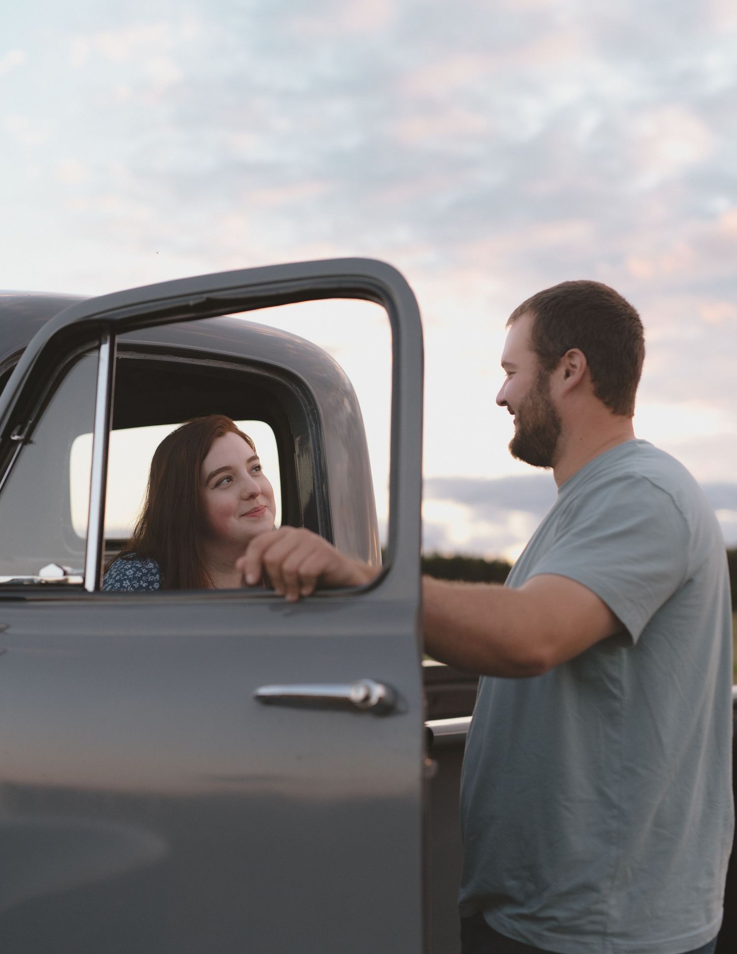 A couple sharing a moment by a vintage truck during sunset.