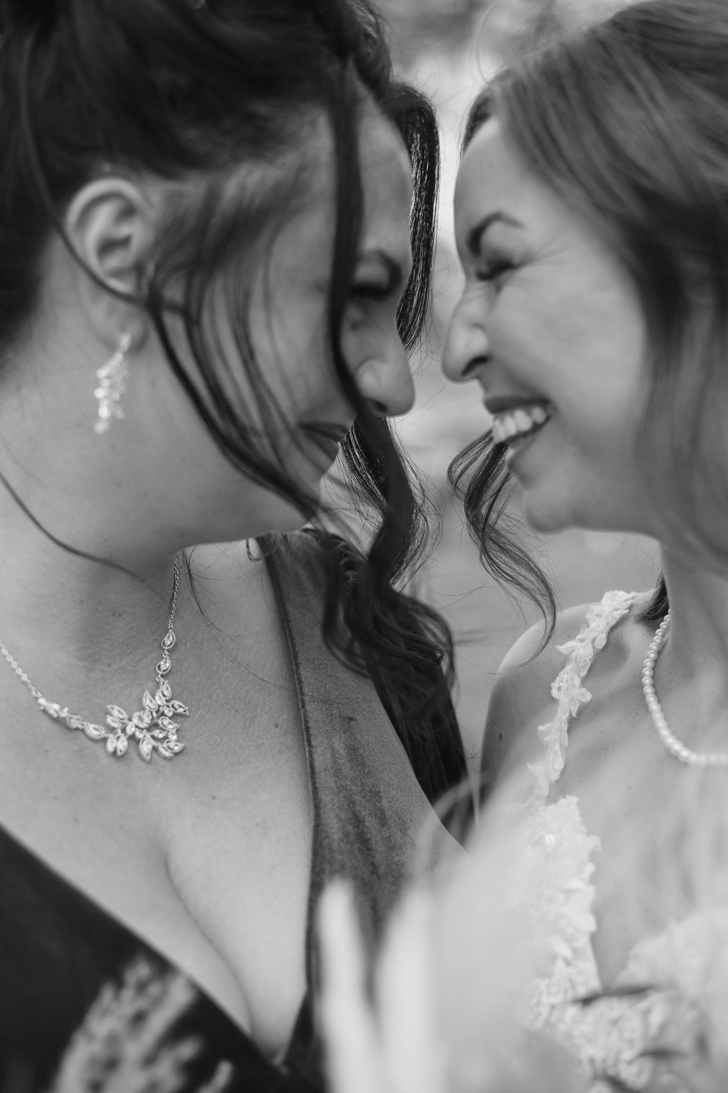 Black and white romantic wedding photo series showing tender close-up moments between two brides wearing elegant jewelry.