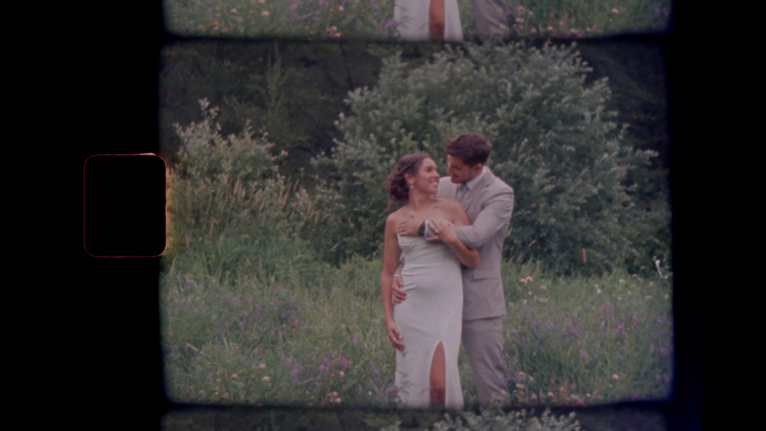 Couple embracing in a meadow, shot on vintage film with natural greenery backdrop, romantic outdoor wedding photography.