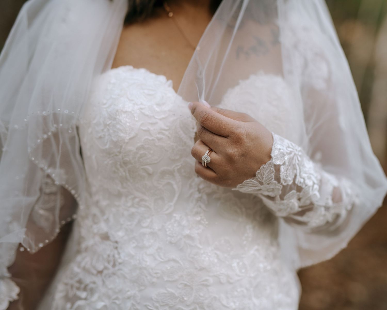 Close-up details of delicate white lace and beading on a wedding dress with sheer fabric and intricate embellishments.