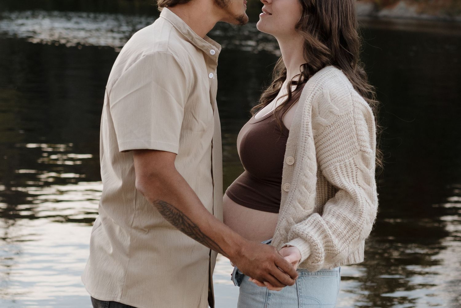 A tender embrace shared between two people by the waterfront at sunset.