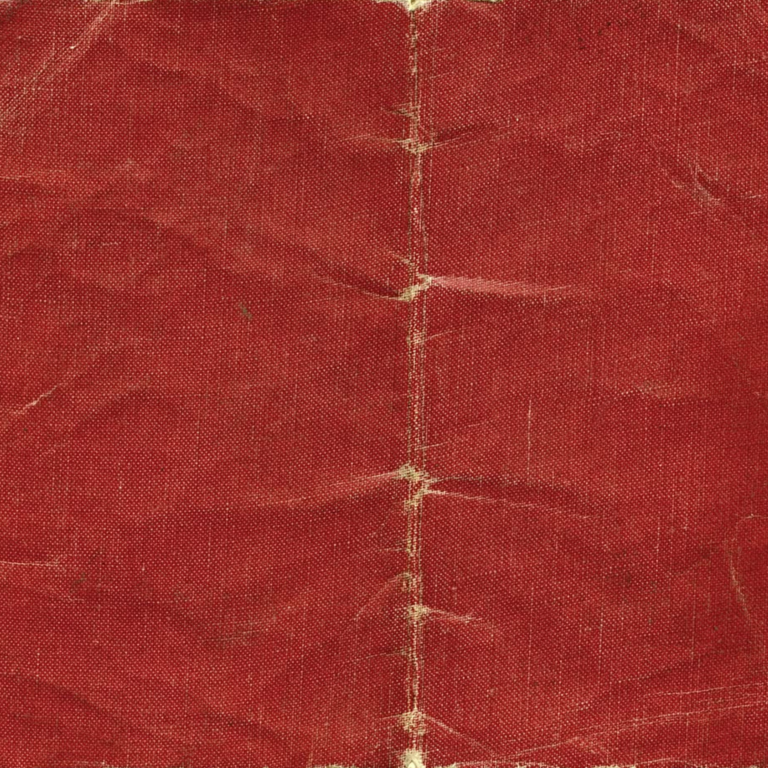 Aged red fabric texture with visible creases, stitching, and worn patina on a vintage textile surface.