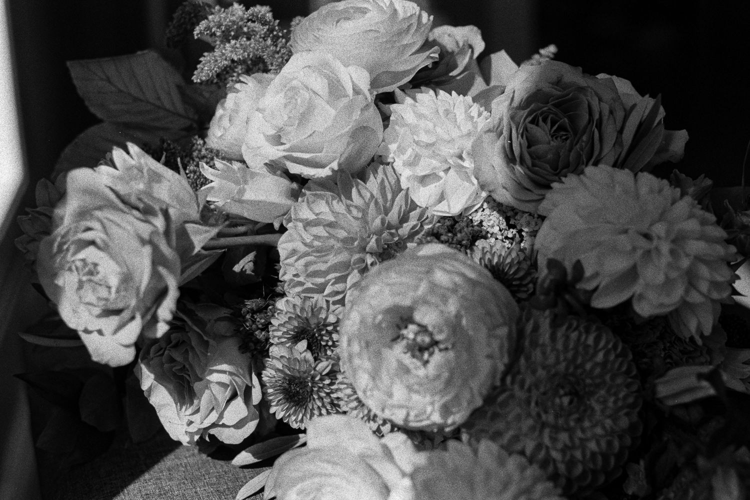 Dramatic film photo of wedding floral arrangement with roses and dahlias for a Sudbury Ontario fall wedding.