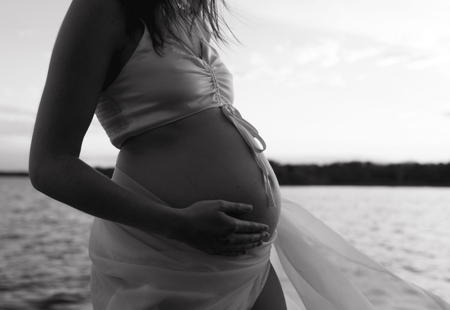 Black and white maternity photo series showing pregnant belly silhouettes against soft lighting.