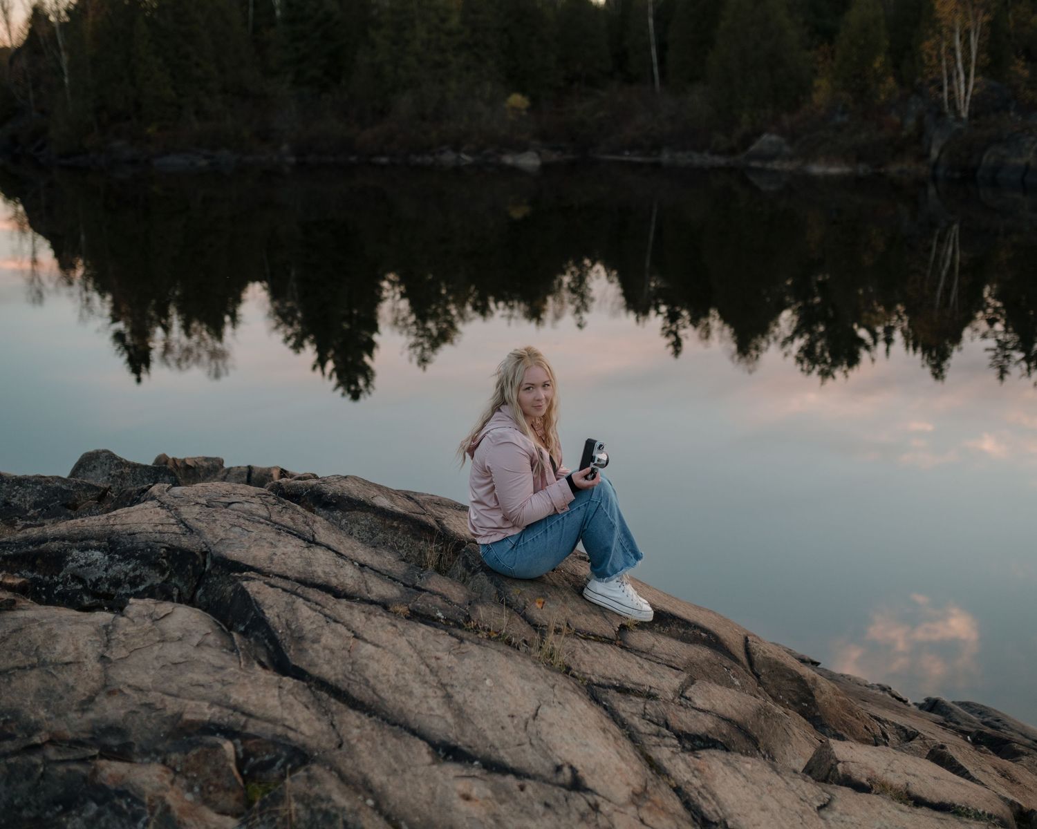 Scenic lakeside photoshoot at sunset with rocky shoreline and reflective water.