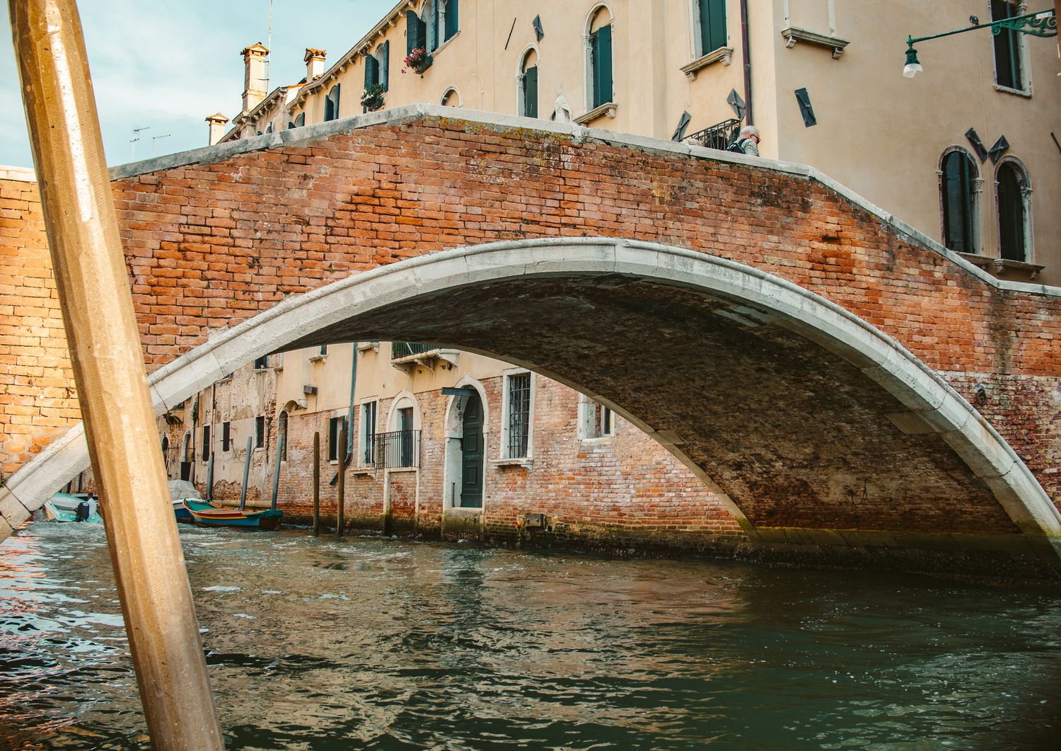 A classic brick arch bridge over a Venetian canal with historic buildings in Venice, Italy.