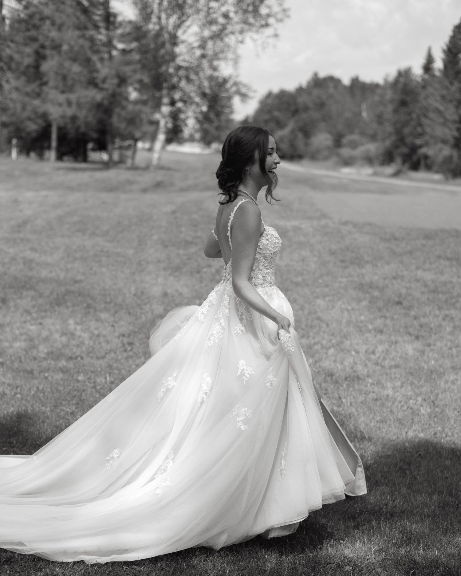 A bride twirls in a flowing white ballgown on a grassy field.