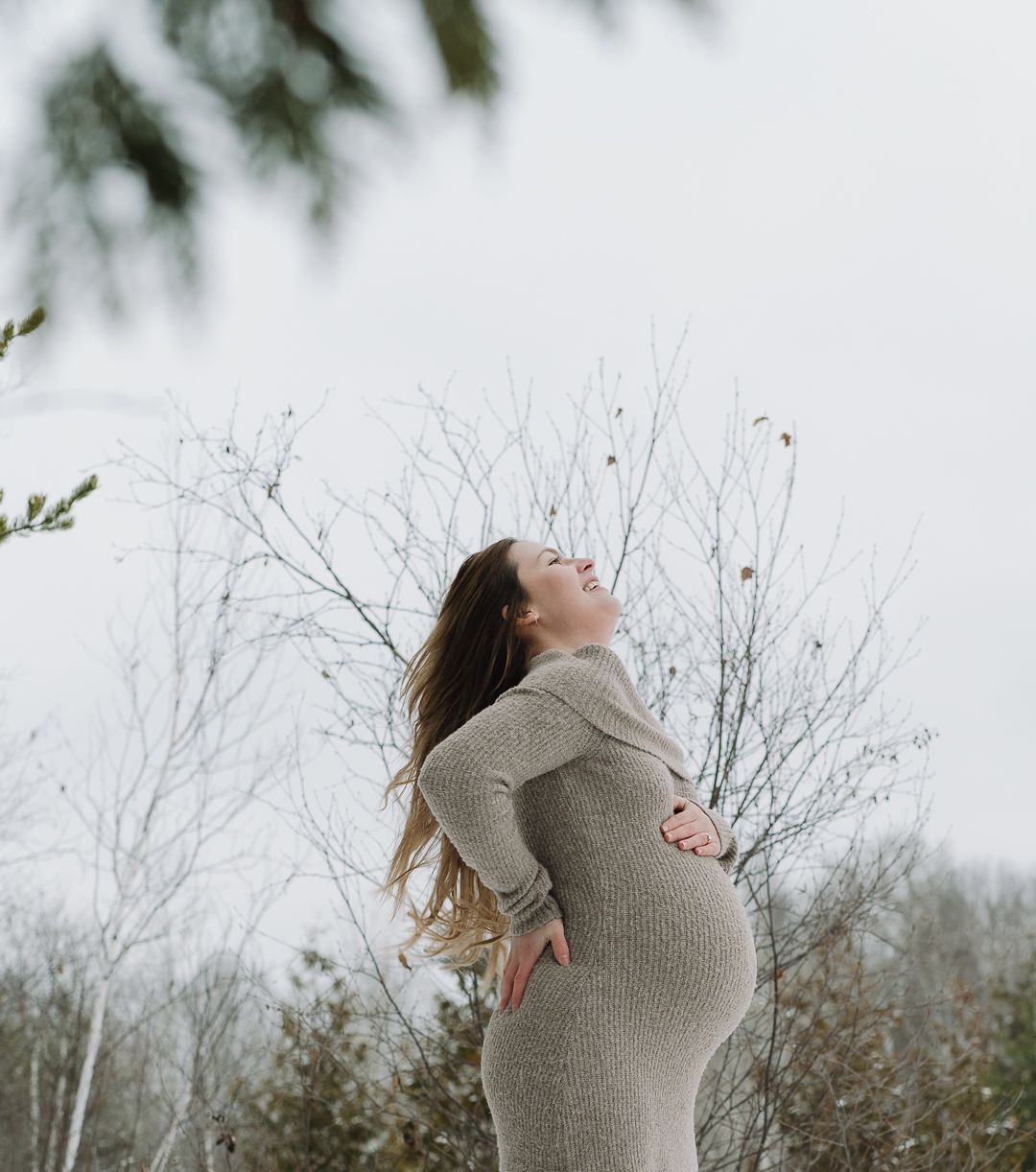 Joyful maternity portrait taken outdoors in winter weather.